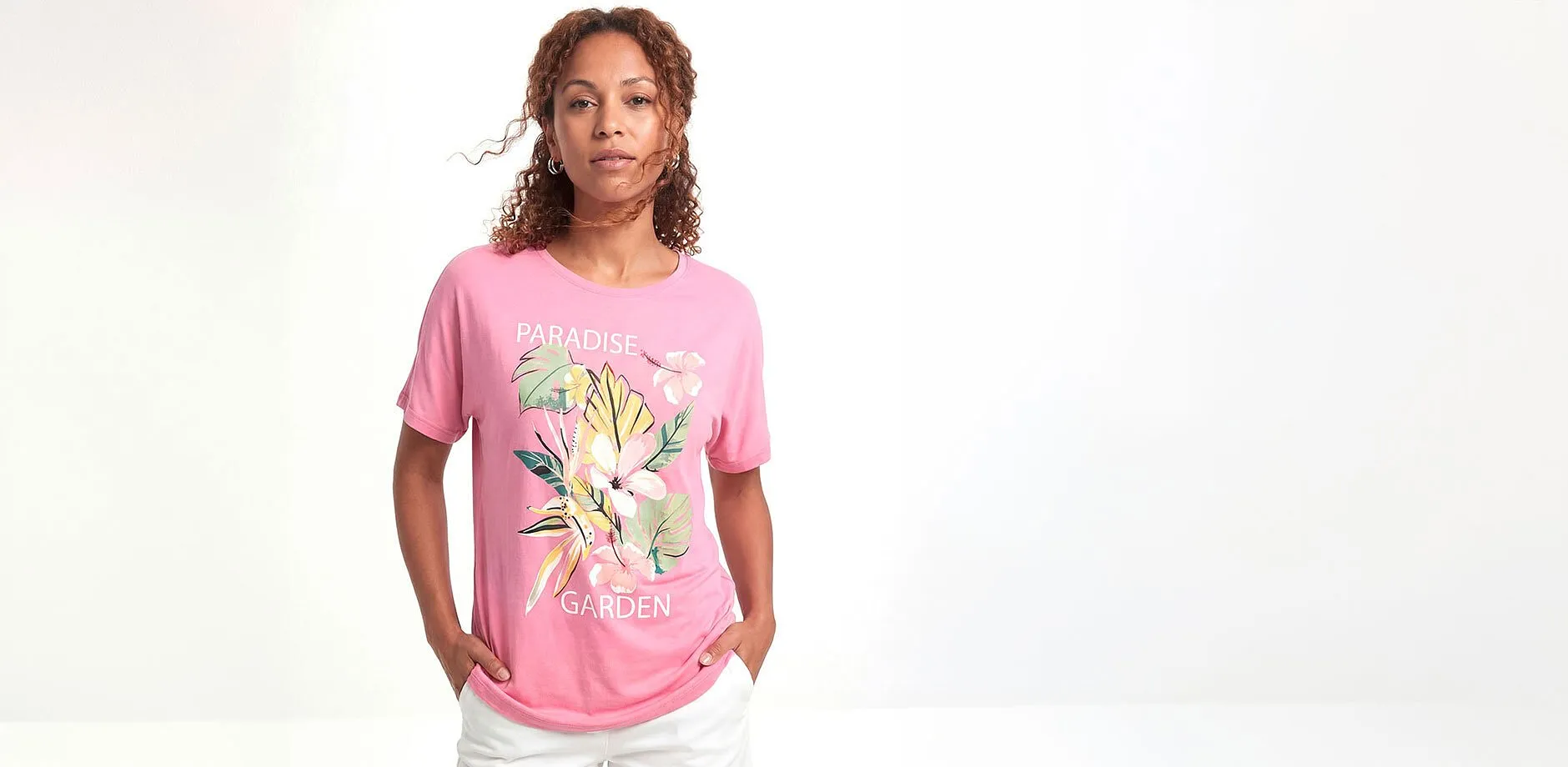 Maglietta rosa con motivo floreale e pantaloni bianchi.