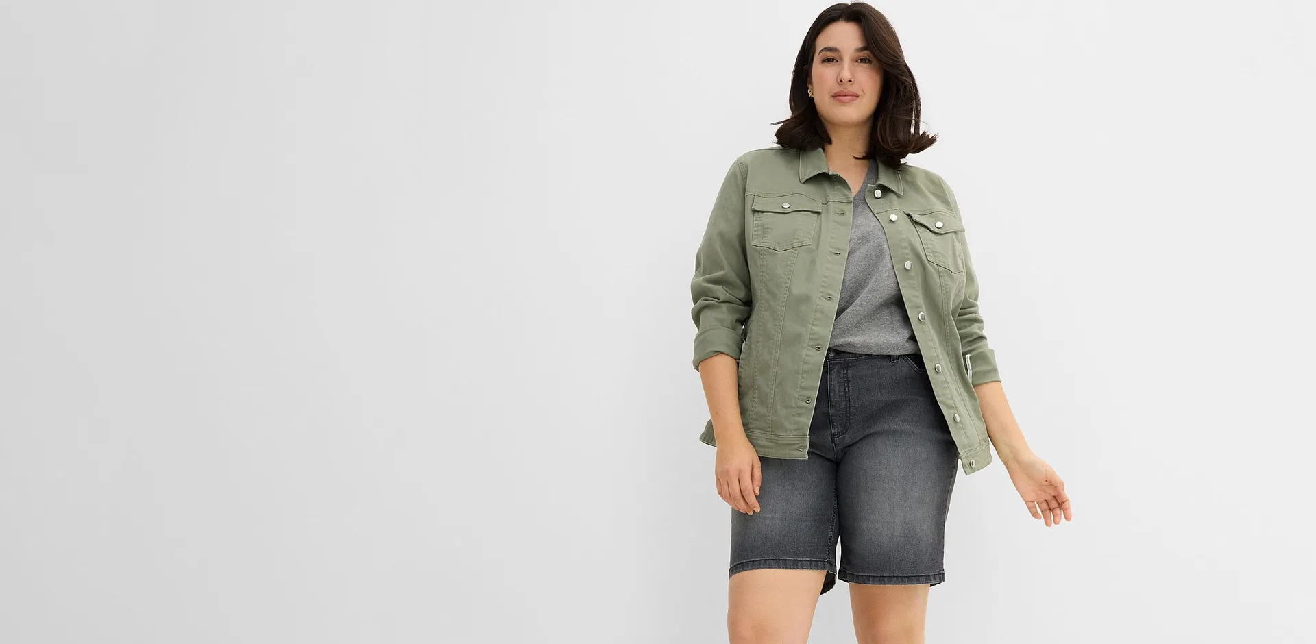 Outfit composto da giacca verde, top grigio e pantaloncini abbinati.
