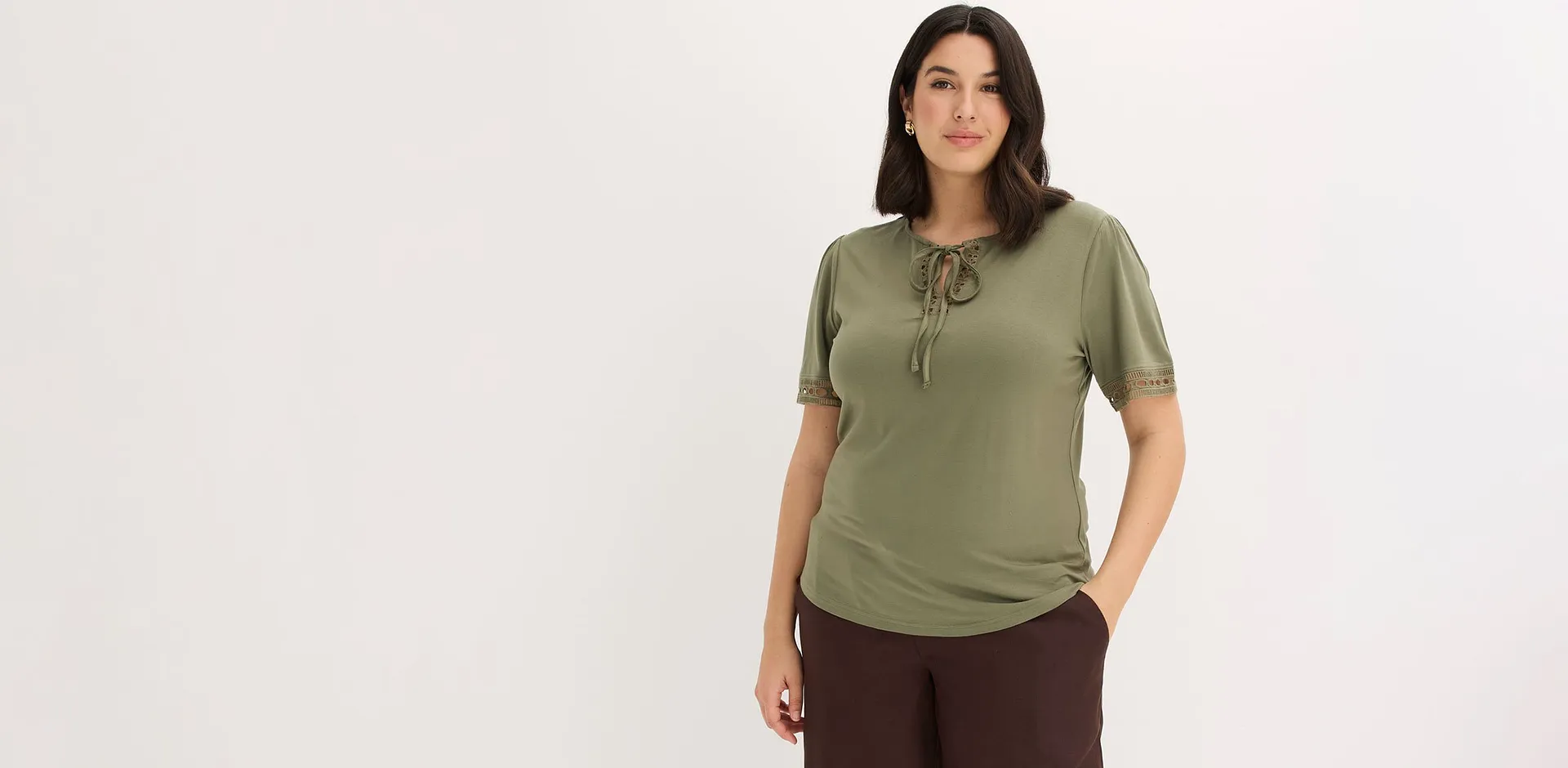 Maglietta verde oliva abbinata a pantaloni marroni.