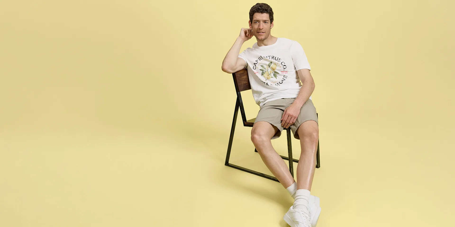 Look estivi con bermuda beige, maglietta bianca e comode sneakers.