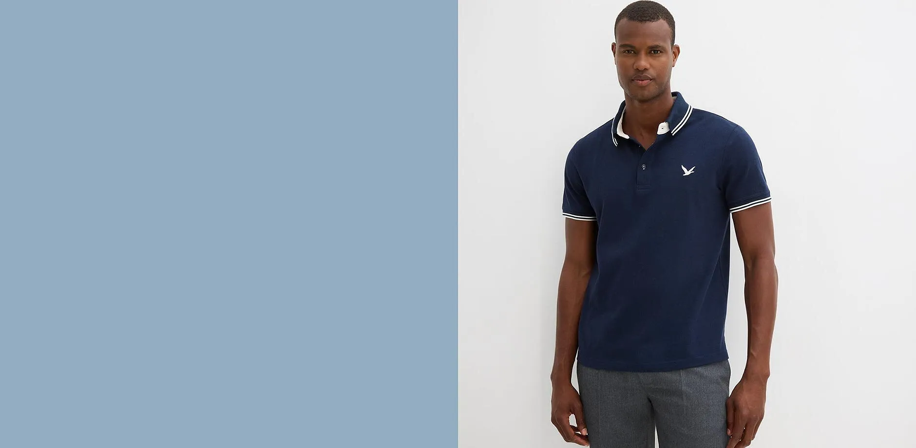 Elegante polo blu scuro con strisce bianche a contrasto e pantaloni grigi per l'uomo moderno.