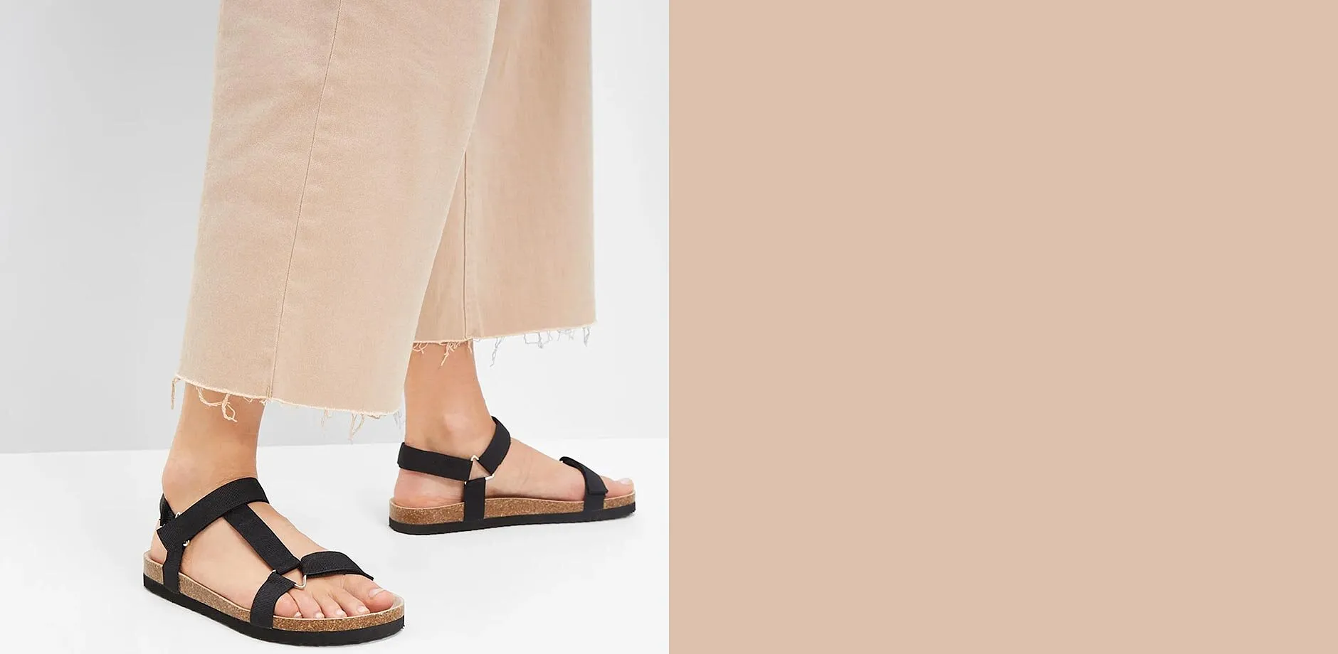 I sandali neri con cinturini si abbinano perfettamente ai pantaloni larghi beige, creando un look casual.