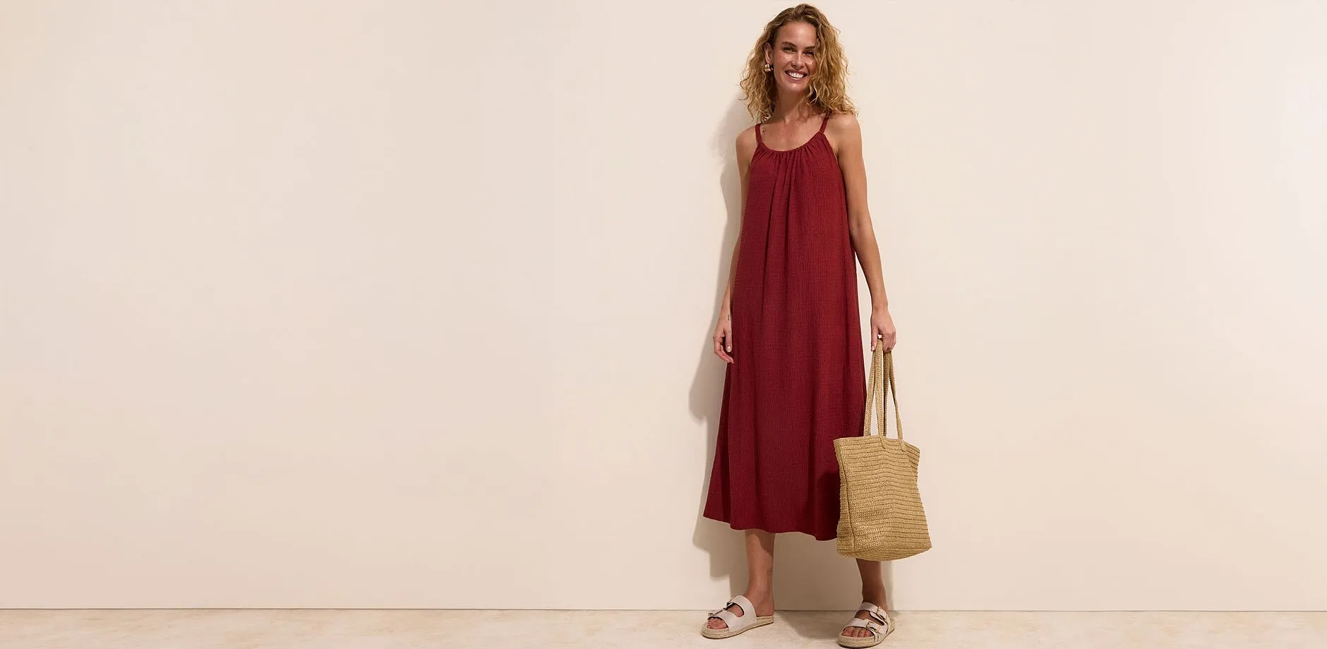 Un abito lungo rosso, comodi sandali e una borsa di vimini.