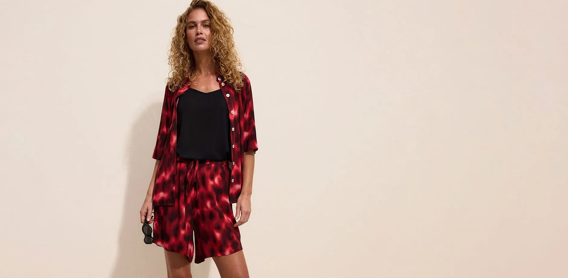 Set batik rosso e nero composto da camicia aperta, pantaloncini e top nero.
