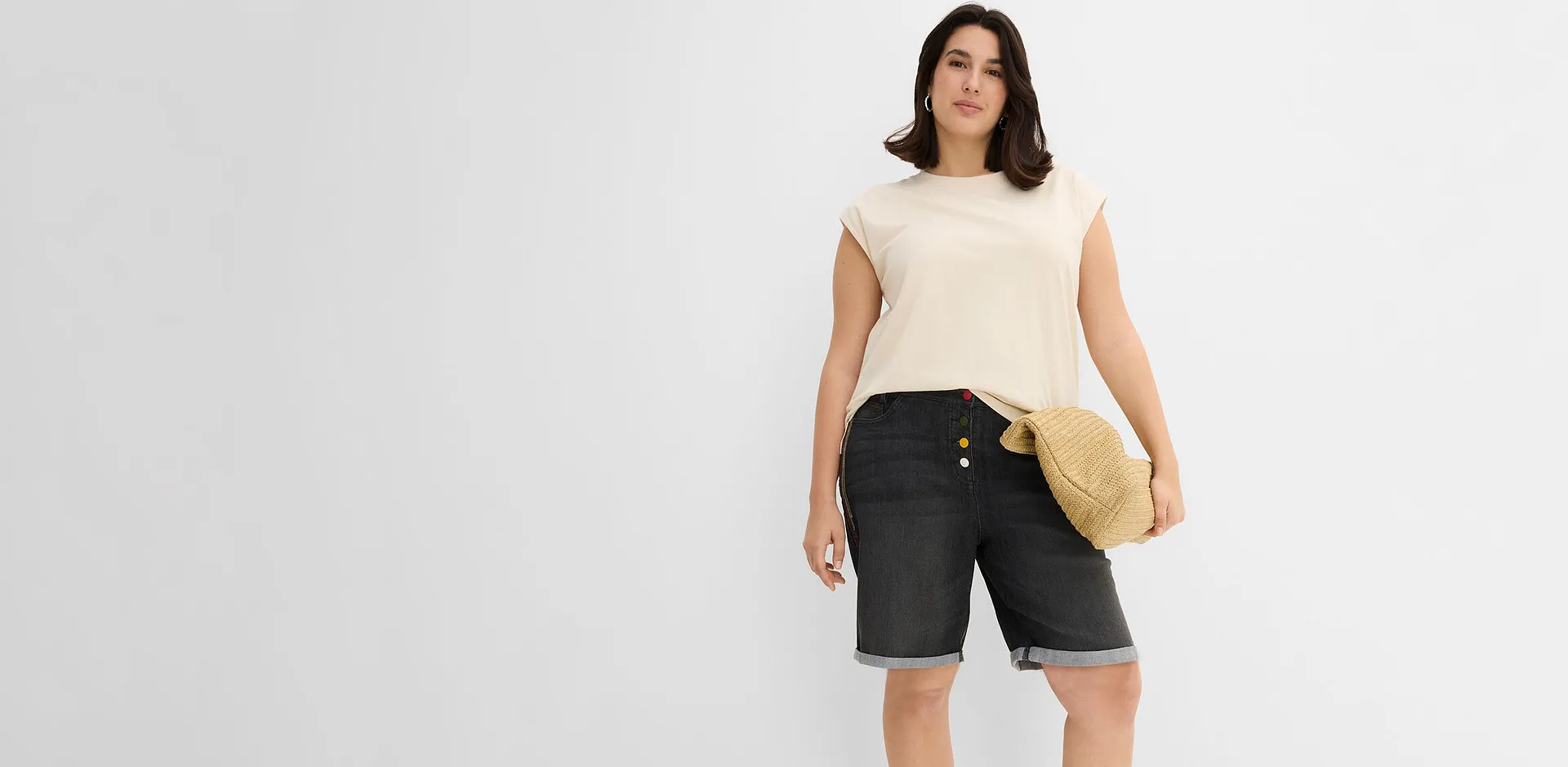 Maglia beige e jeans bermuda scuri con risvolto.