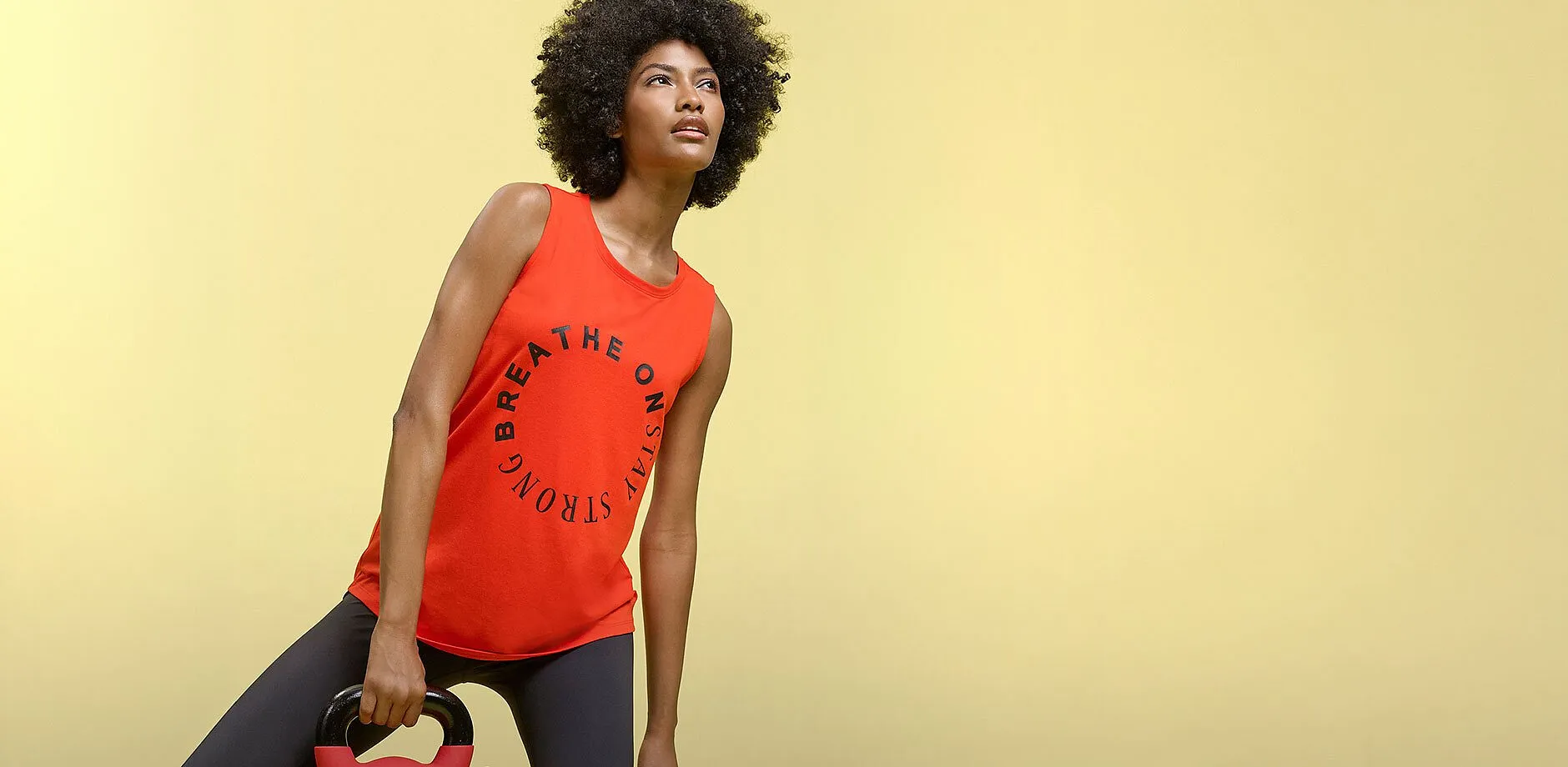 Top rosso senza maniche con scritta e leggings sportivi scuri per l'allenamento.