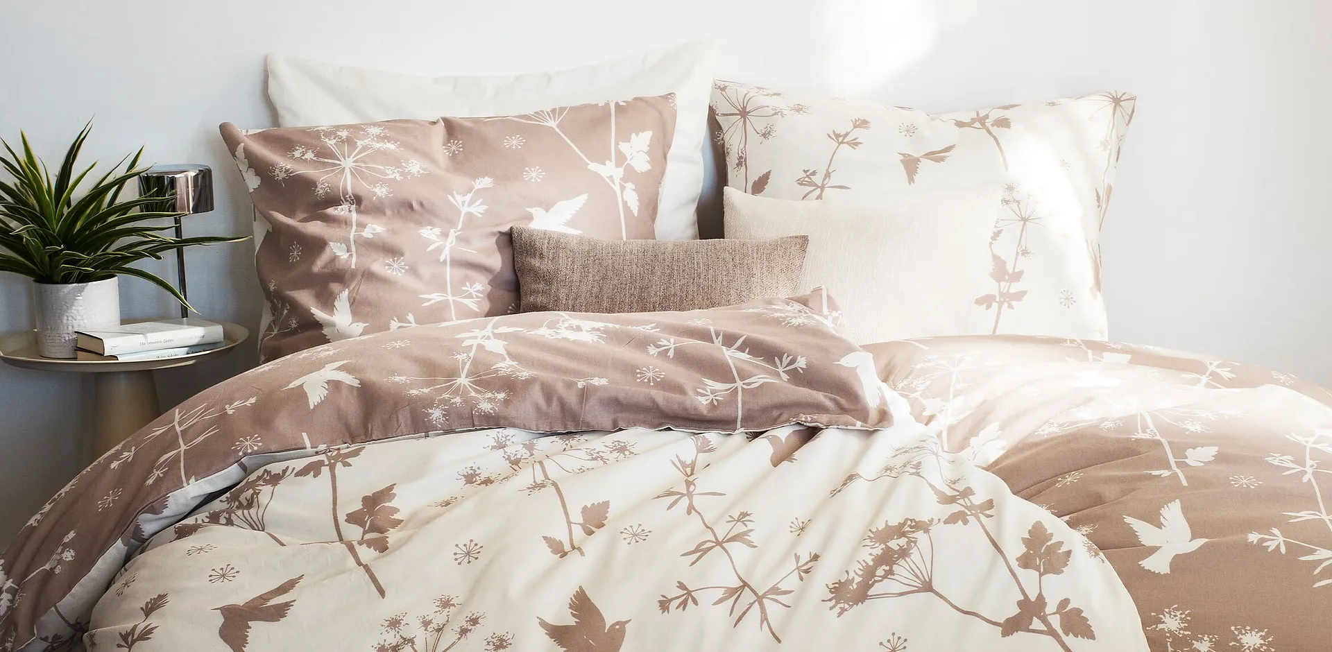 Una linea di biancheria da letto accogliente con delicati motivi floreali e di uccelli in tonalit&agrave; naturali di marrone.