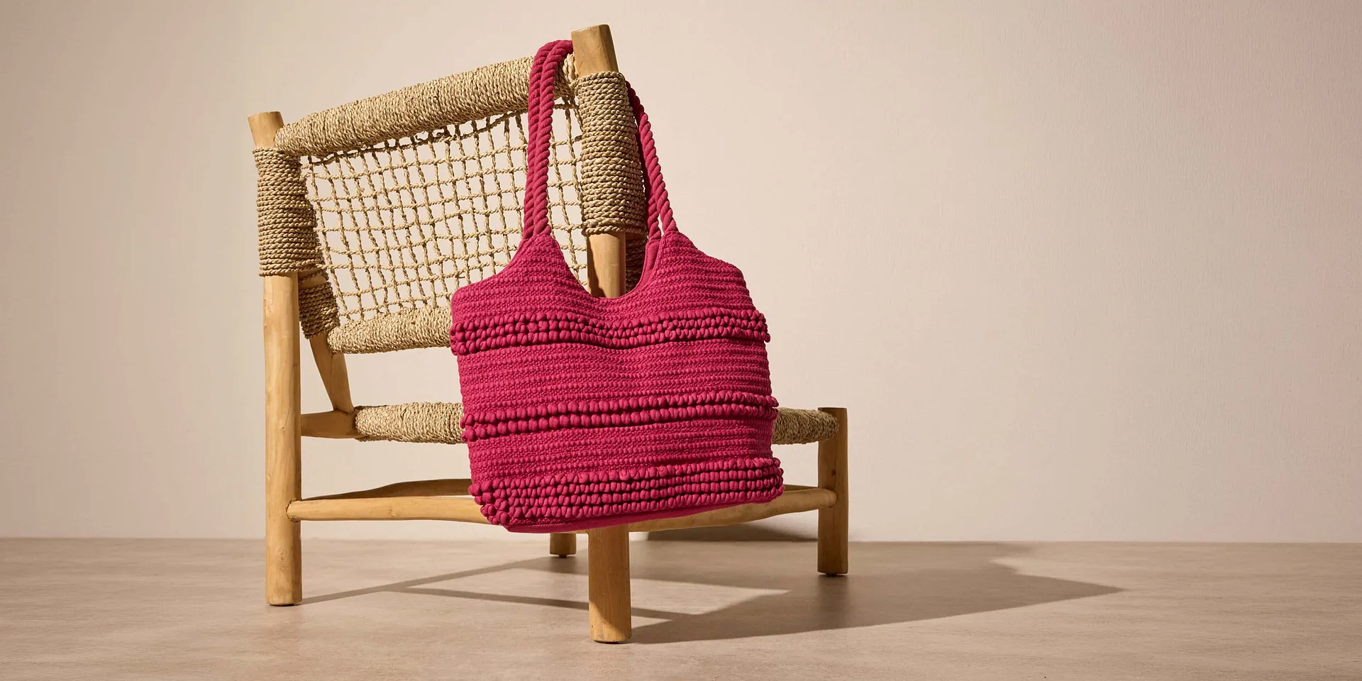 Borsa rosa lavorata all&rsquo;uncinetto con superficie testurizzata.