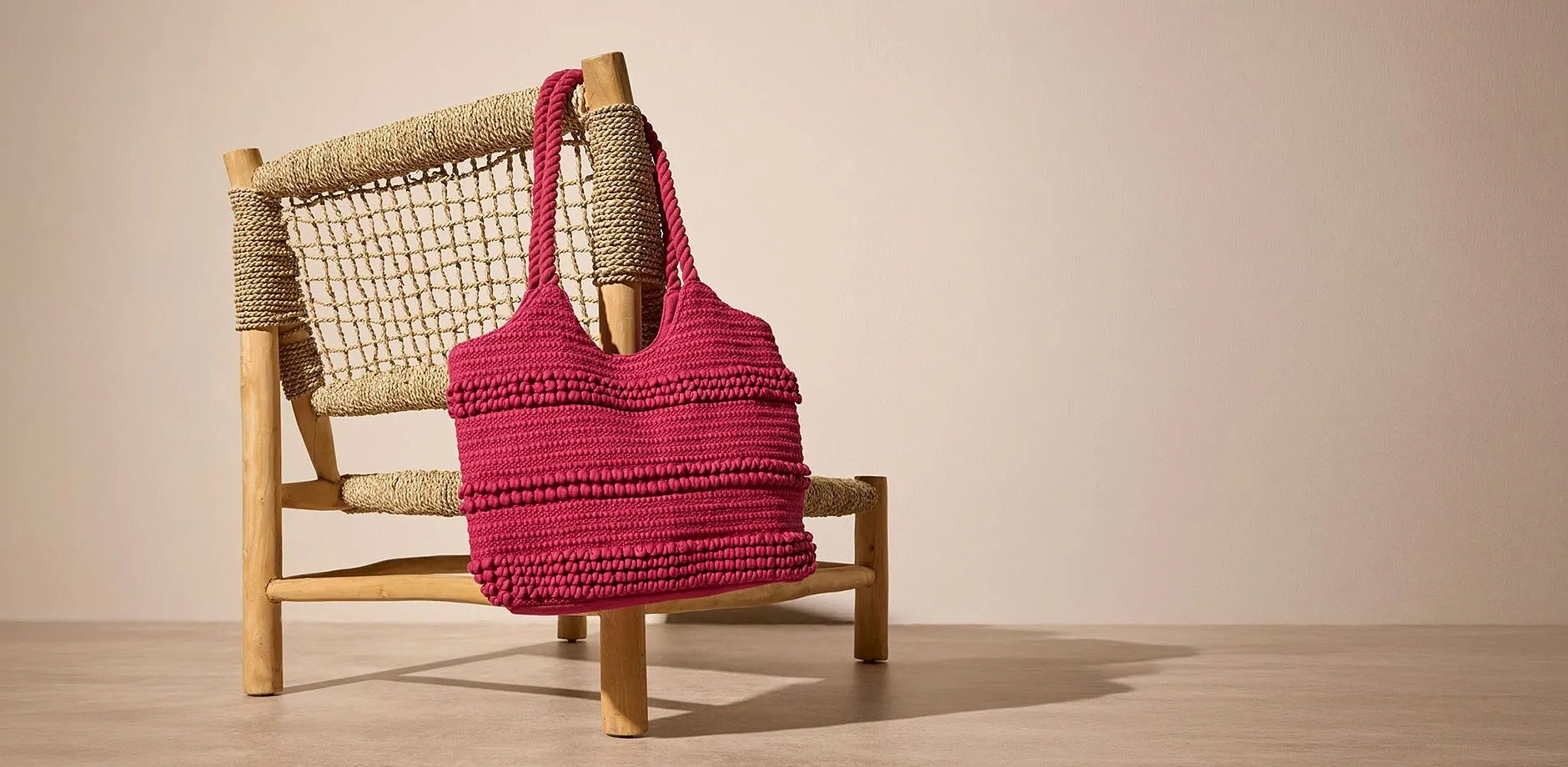 Borsa rosa lavorata all&rsquo;uncinetto con superficie testurizzata.