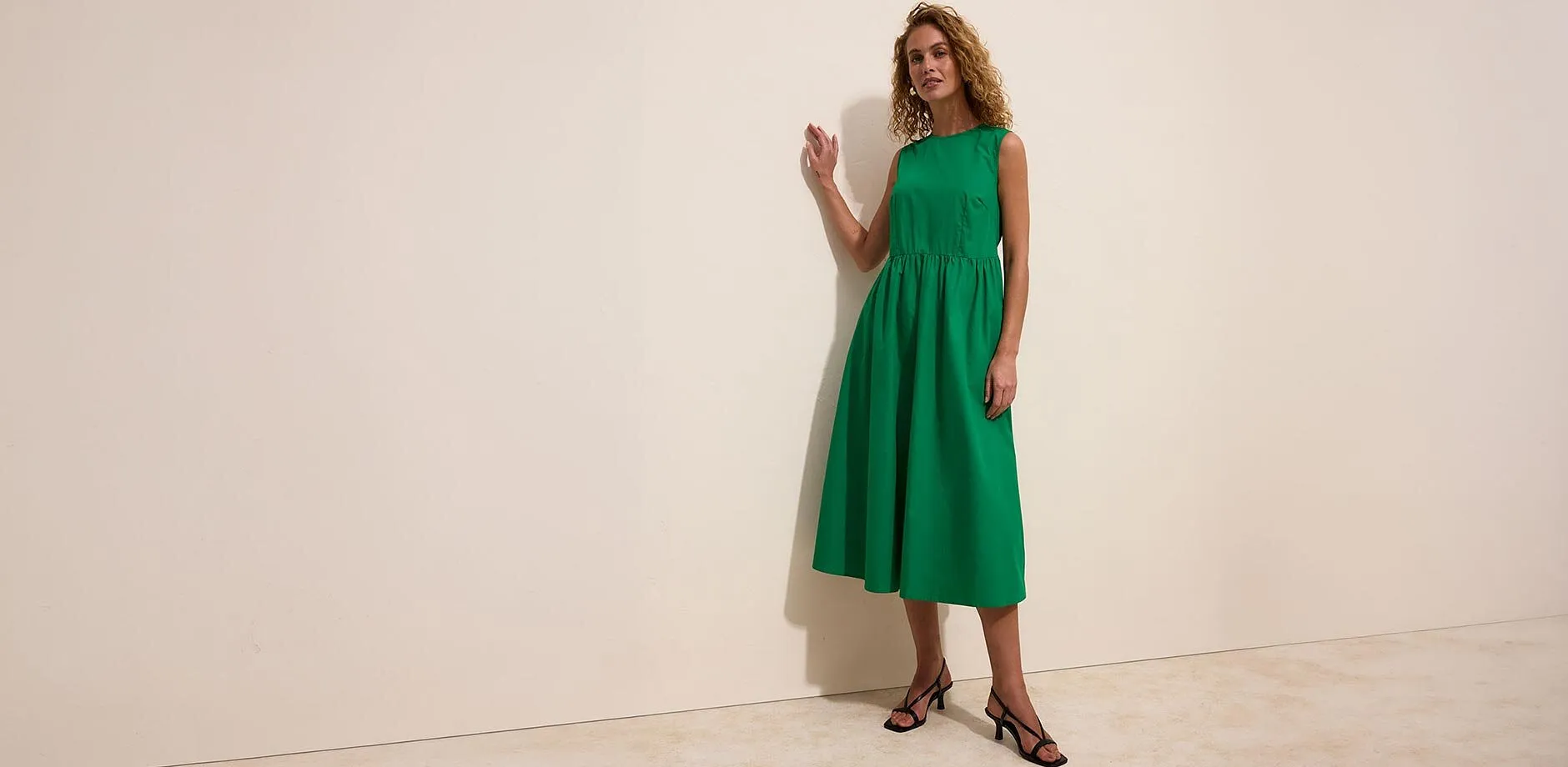 Abito midi verde con sandali neri allacciati.