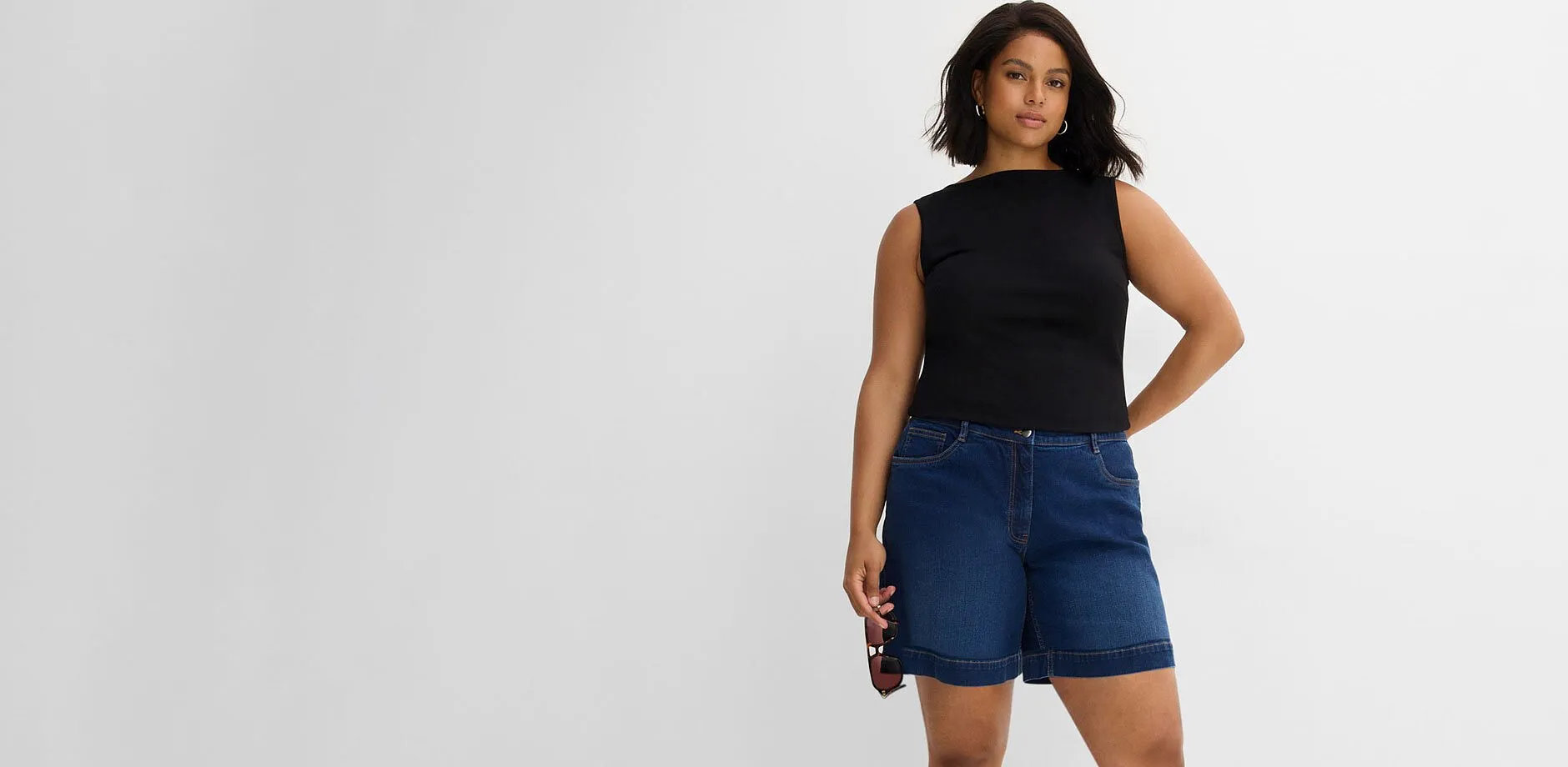 Top nero e shorts di jeans blu dal look casual.