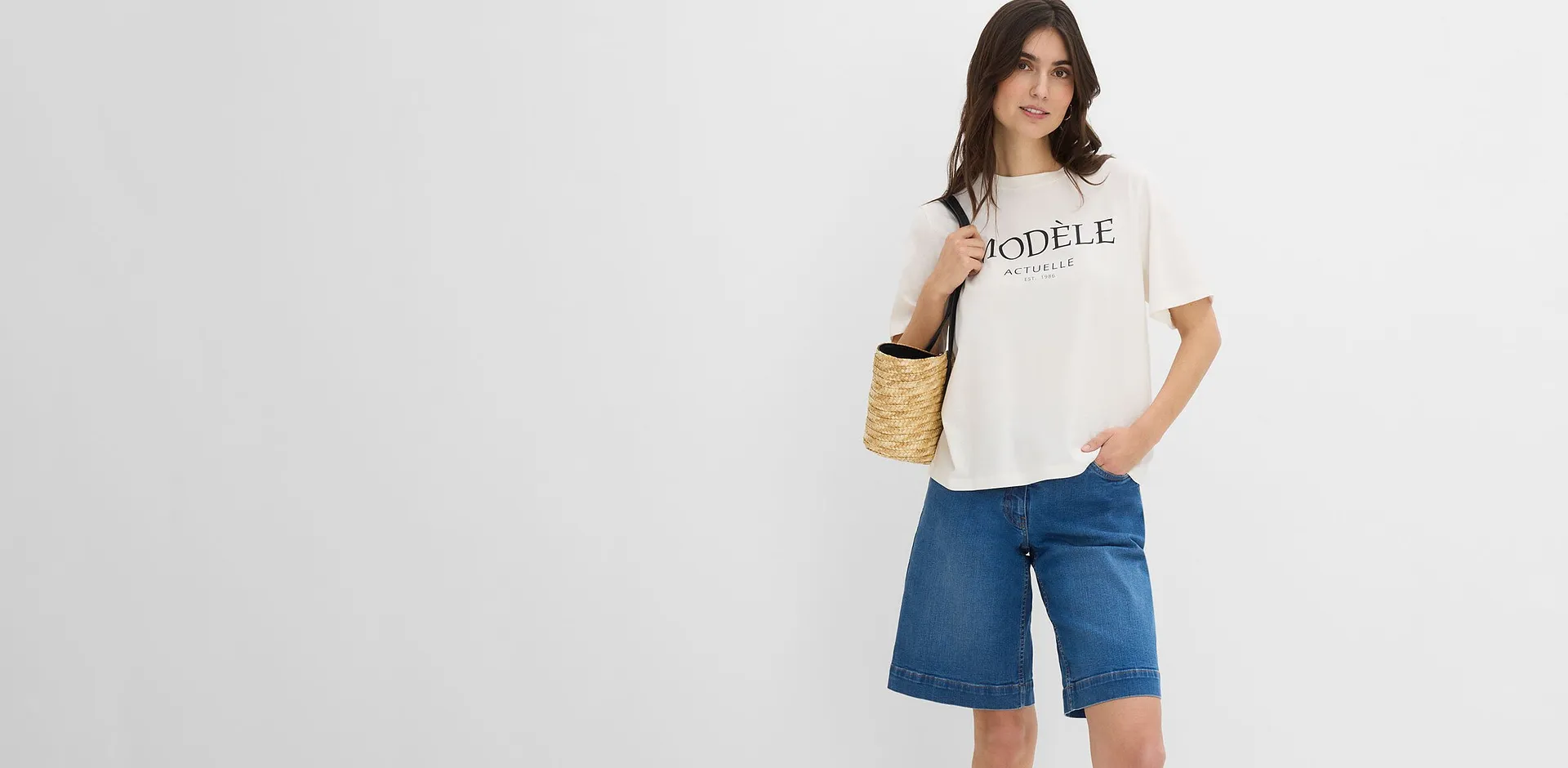 Maglietta bianca casual con una scritta e dei bermuda larghi di jeans blu.