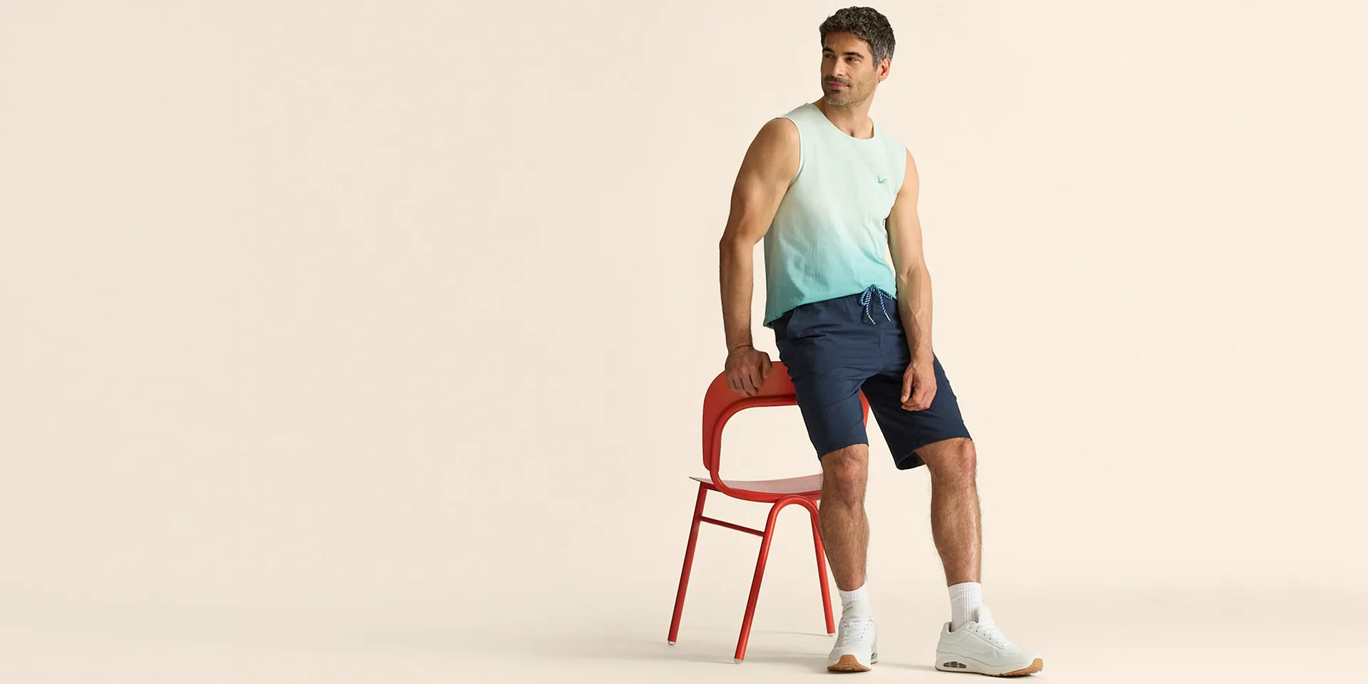 Canotta trendy dai colori sfumati, abbinata a pantaloncini blu e sneaker bianche.