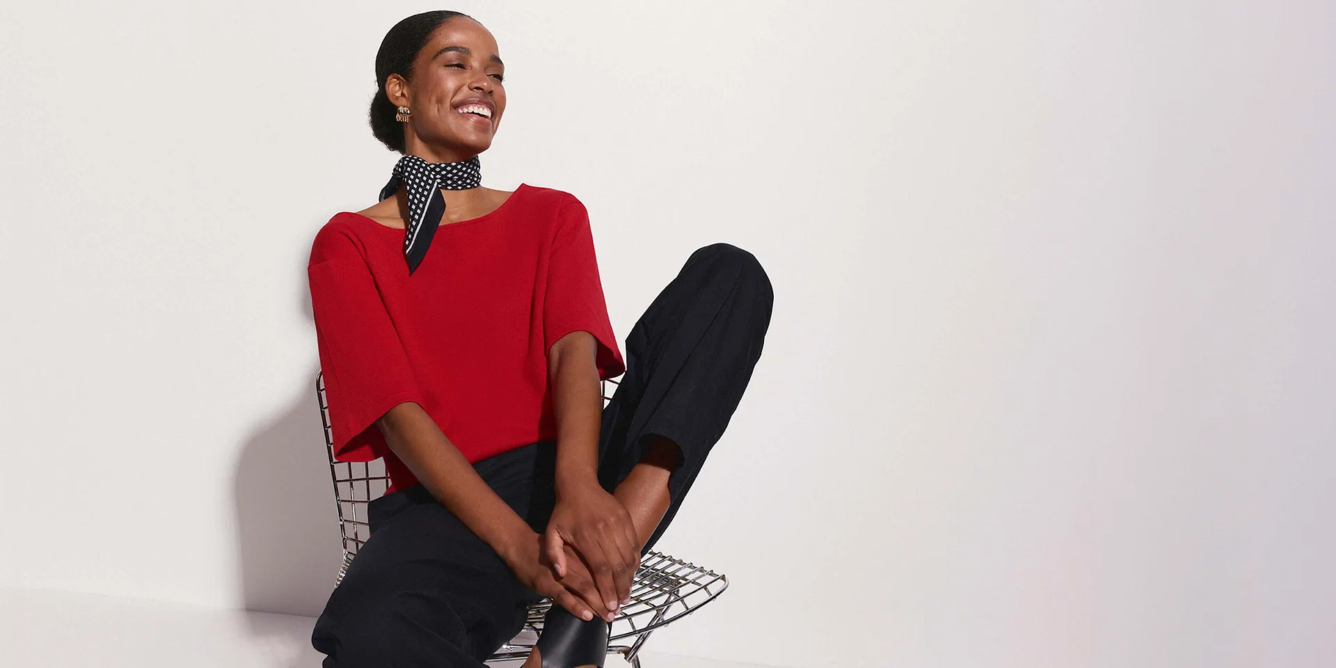 Stupenda con maglia rossa, pantaloni neri e foulard a pois.
