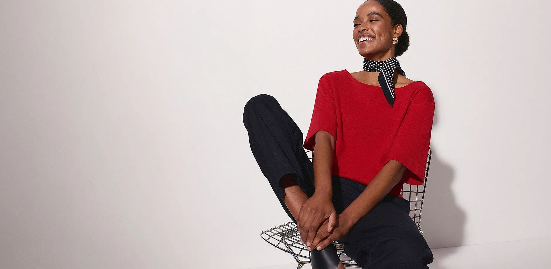 Outfit con maglia rossa, pantaloni neri e foulard a pois.