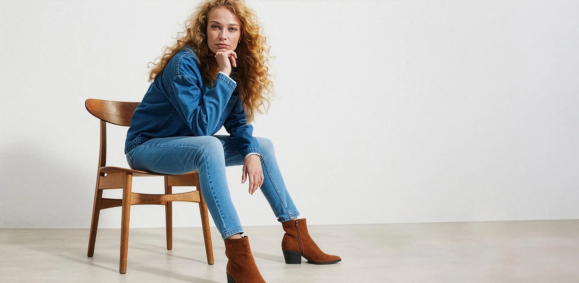 Giacca di jeans blu, jeans e degli eleganti stivaletti marroni.