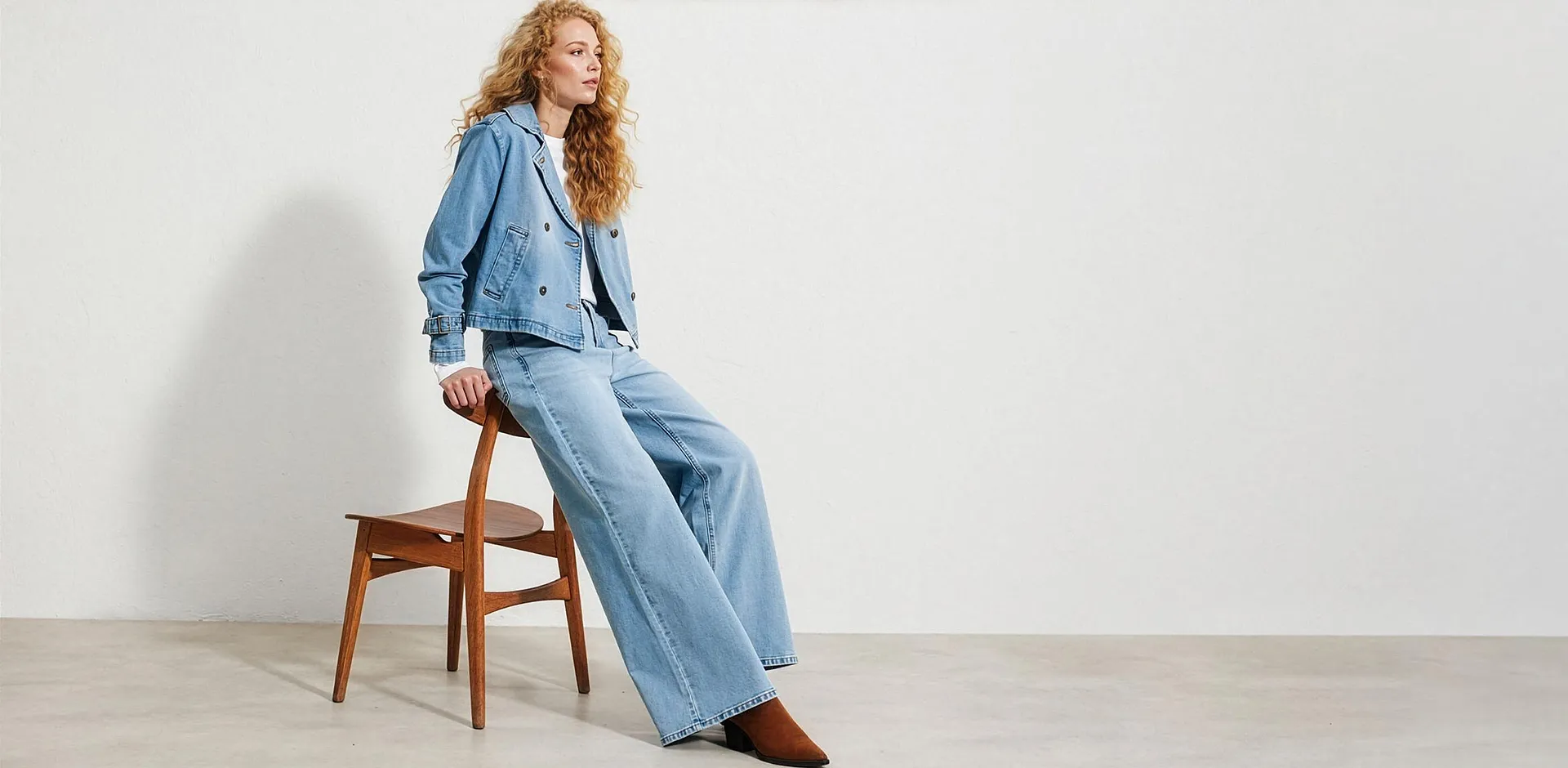 Giacca di jeans corta azzurra, pantaloni larghi e maglietta bianca.