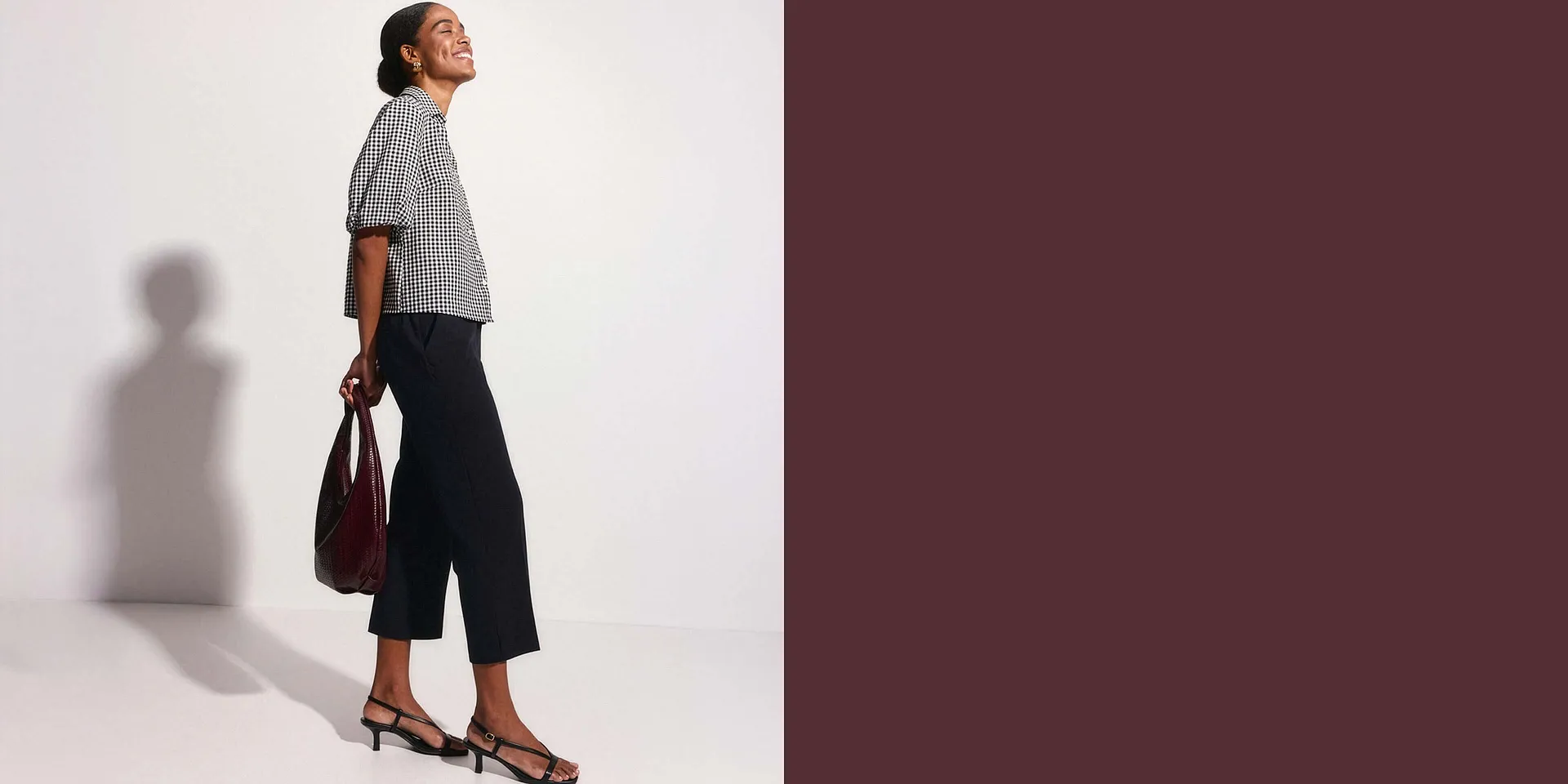 Un abbinamento di classe: camicetta a quadri, pantaloni culotte scuri ed eleganti sandali con cinturini, con borsa.