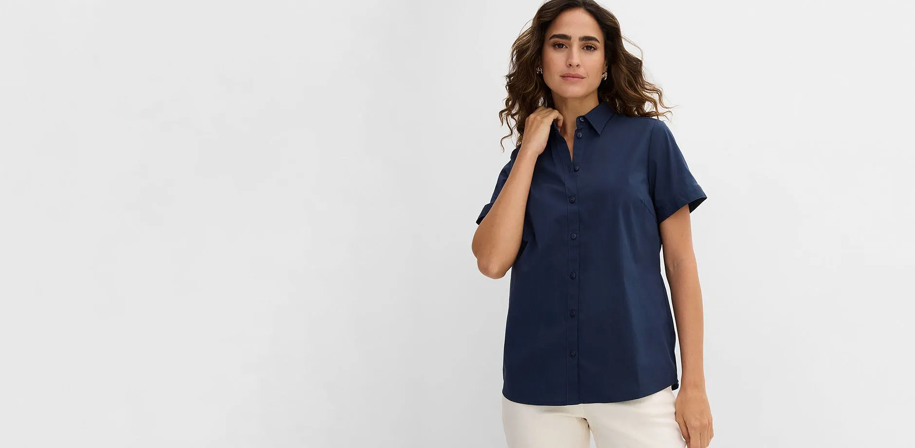 Camicia a maniche corte blu scuro con colletto, abbinata a pantaloni chiari.