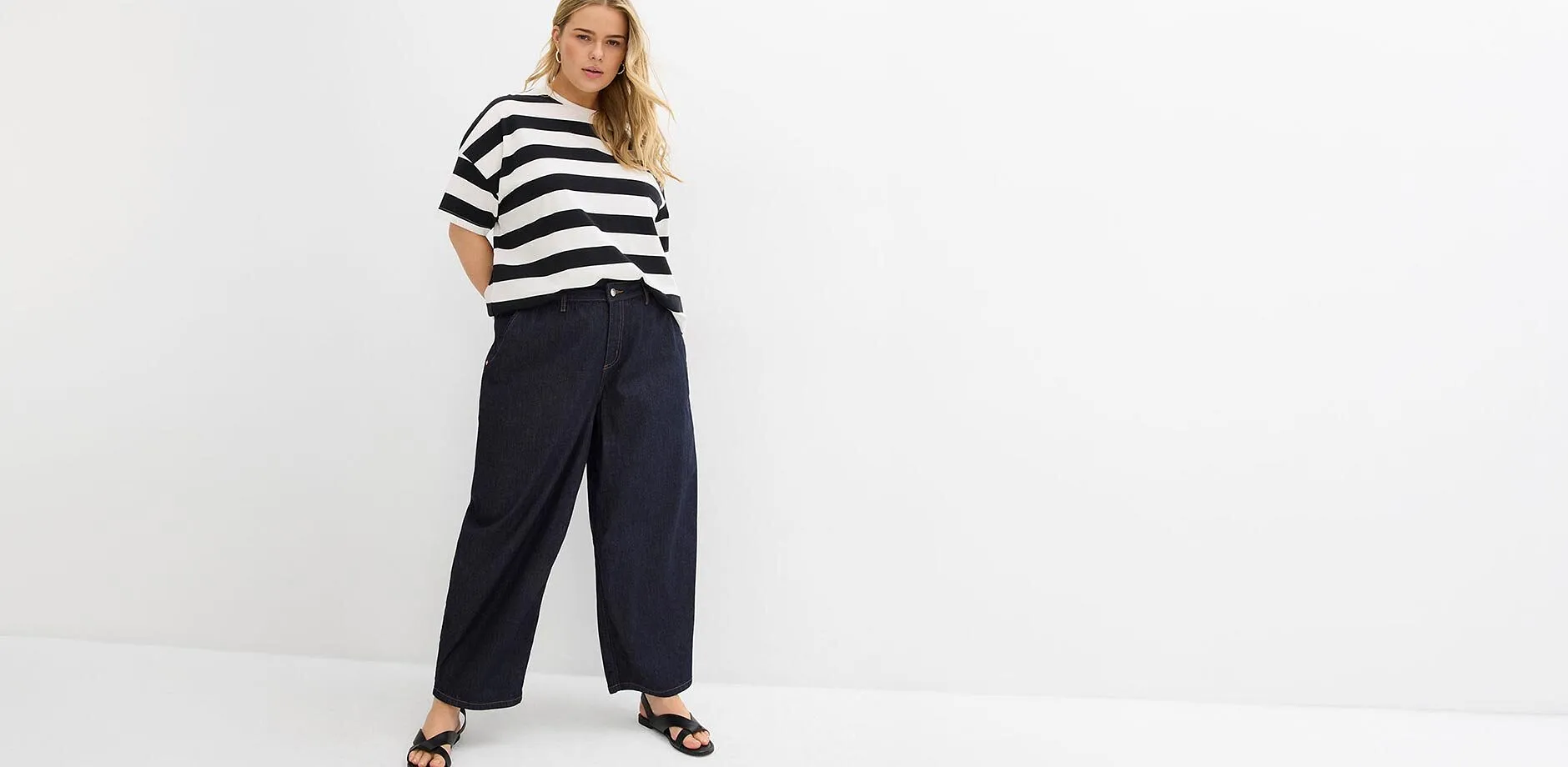 Maglia a righe, jeans larghi blu scuro e sandali neri.