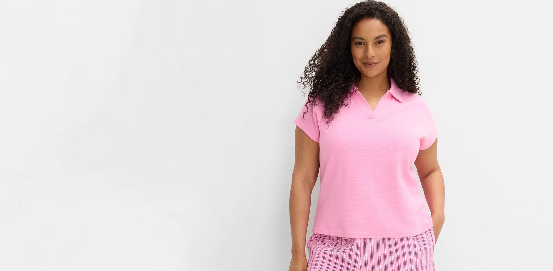 Una polo rosa a maniche corte e un paio di pantaloni a righe.