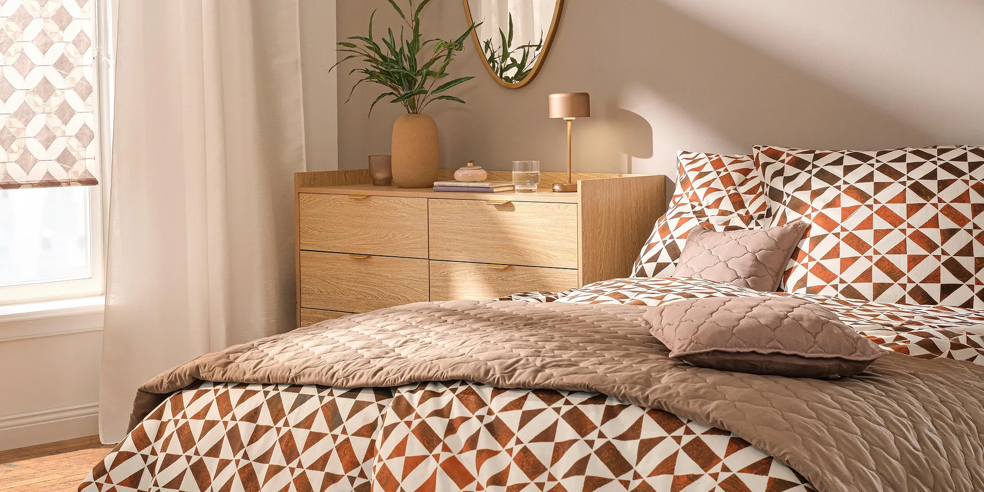 Biancheria da letto a fantasia nei toni del marrone e dell'arancione, con trapunta e cuscini decorativi.