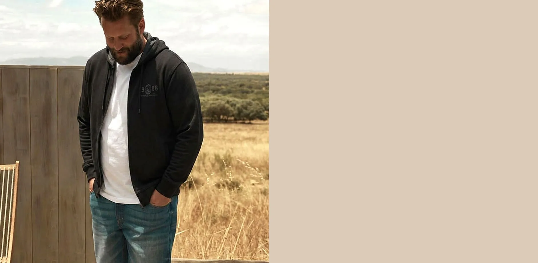 Felpa con cappuccio scura sopra una maglietta bianca, abbinata a jeans blu: uno stile comodo.