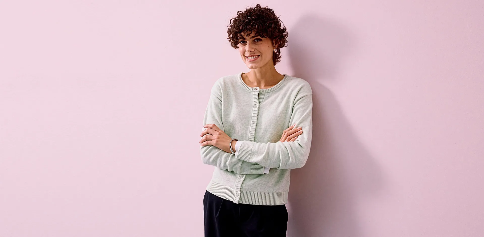 Un cardigan verde chiaro abbinato a un elegante paio di pantaloni neri.
