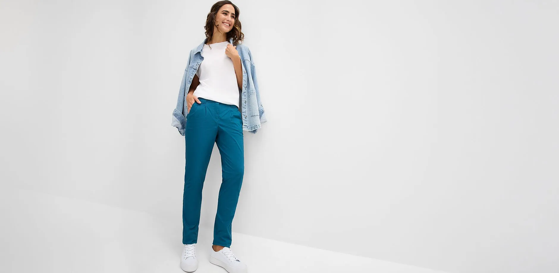 Pantaloni turchesi, maglietta bianca, giacca di jeans casual e sneaker bianche.