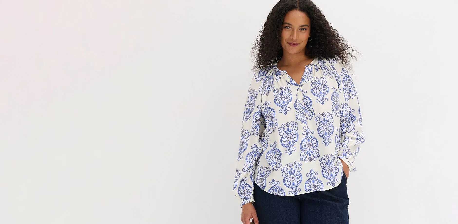 Camicetta bianca a maniche lunghe con un motivo giocoso blu e pantaloni scuri.