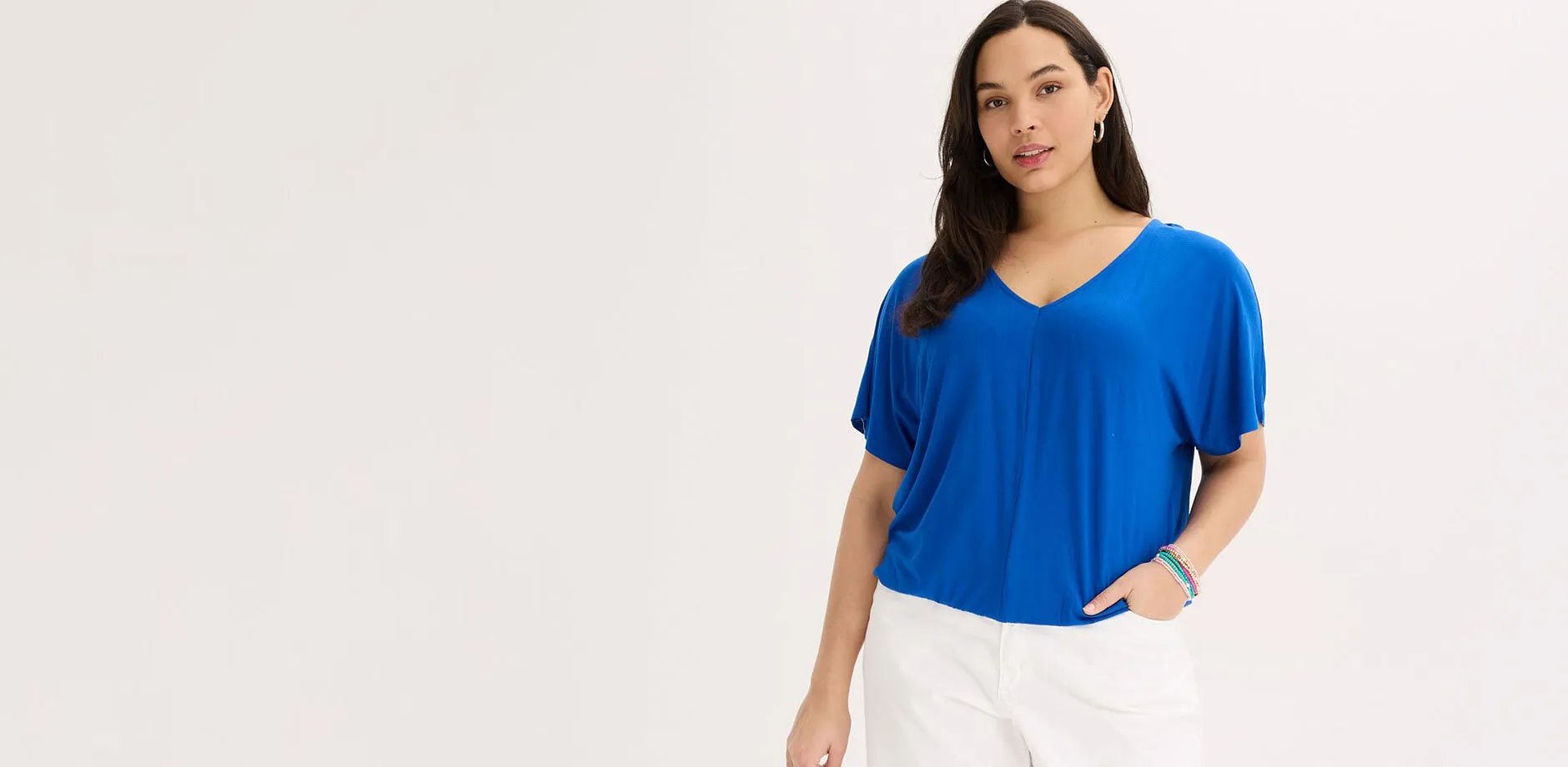 Maglietta blu oversize con scollo a V e pantaloni bianchi.