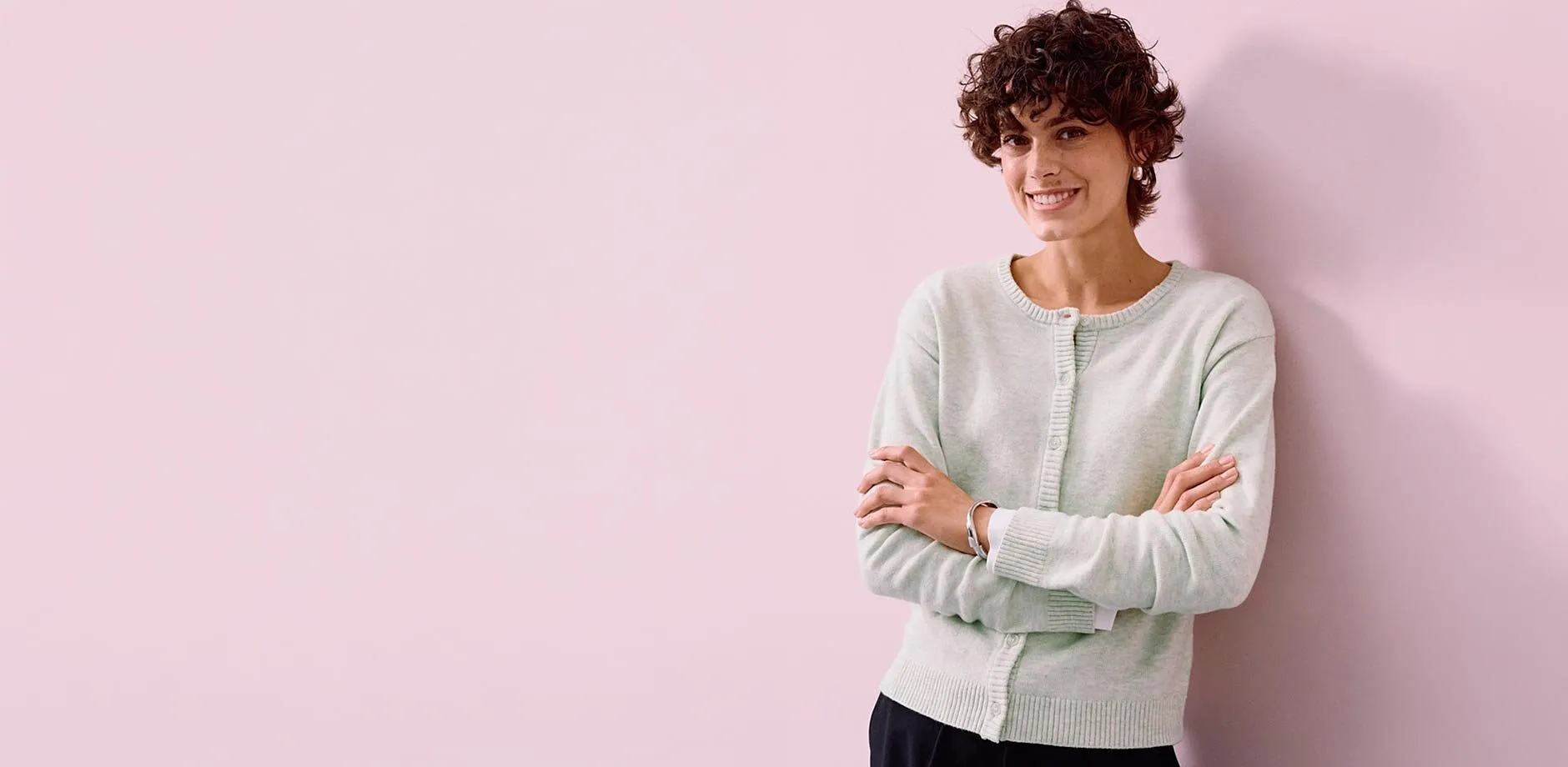 Un cardigan verde chiaro abbinato a pantaloni scuri.