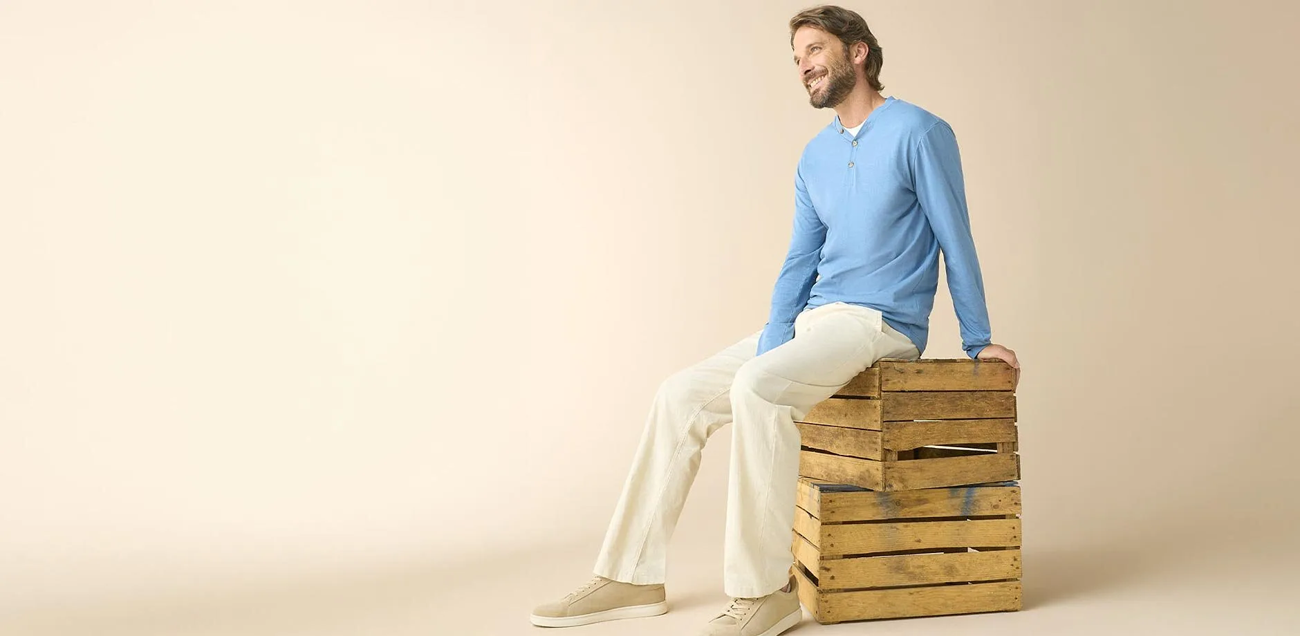 Maglia a maniche lunghe azzurra, pantaloni chiari e sneaker beige.