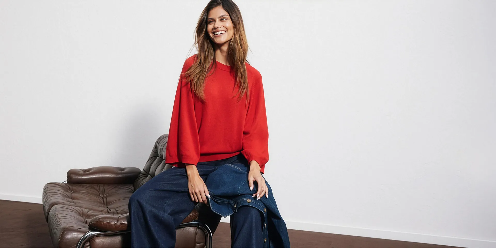 Maglione rosso, jeans larghi e giacca di jeans abbinata.