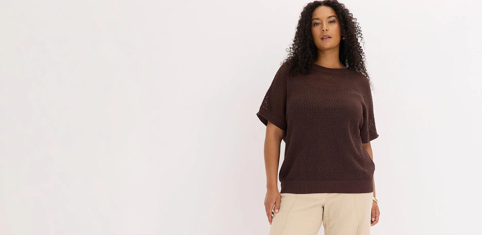Un maglione oversize marrone e un paio di pantaloni chiari.