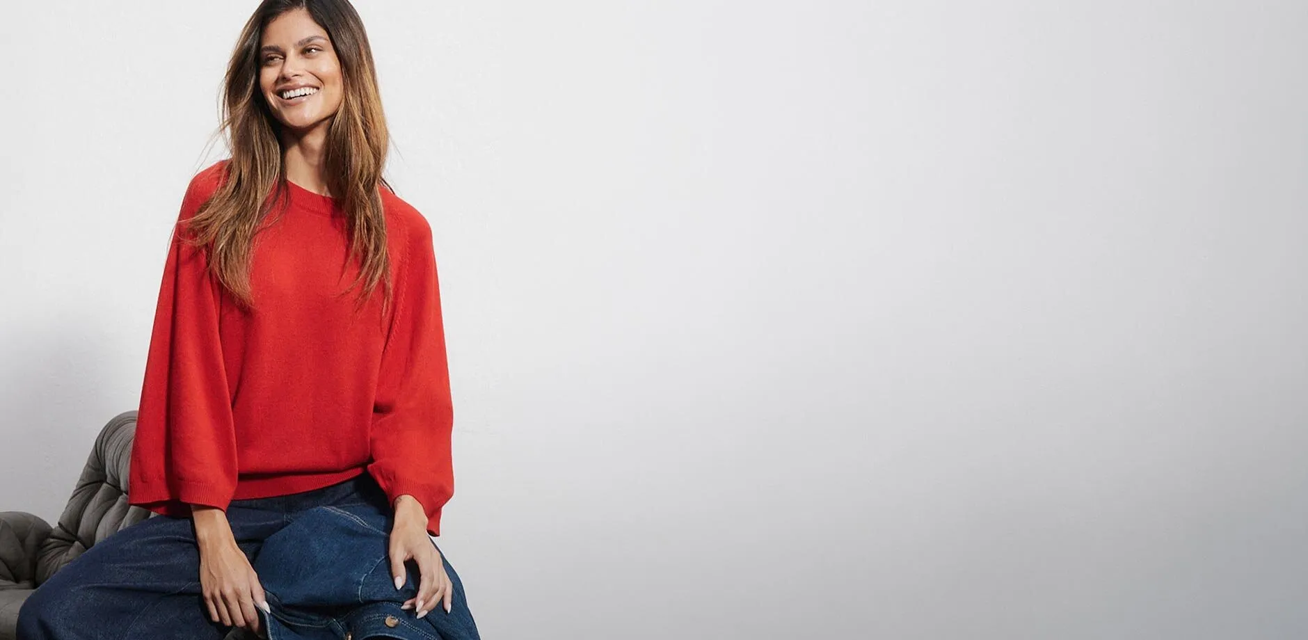 Maglione rosso con maniche larghe, abbinato a jeans blu e una giacca di jeans.