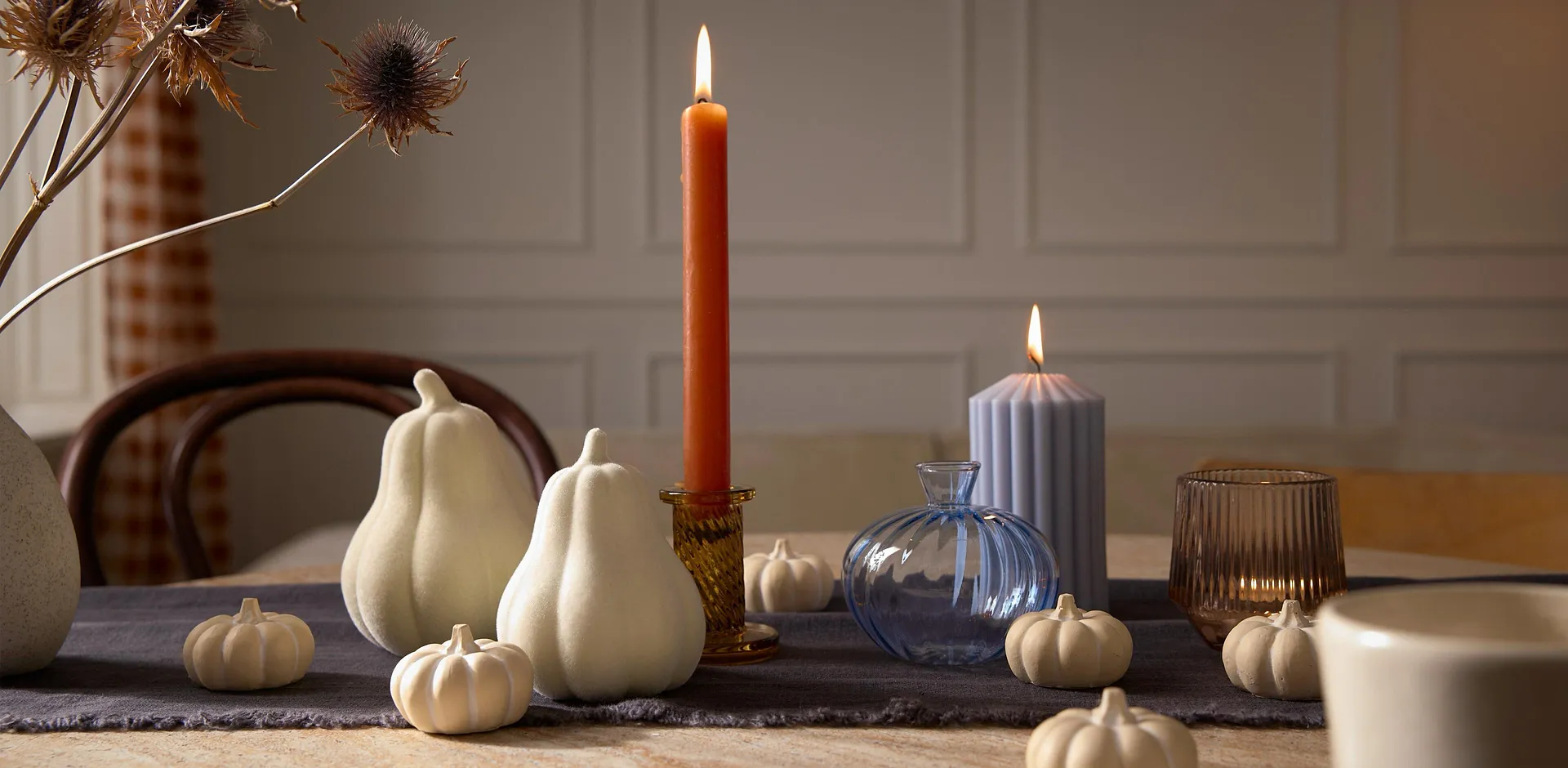Decorazione autunnale con zucche bianche e una candela.