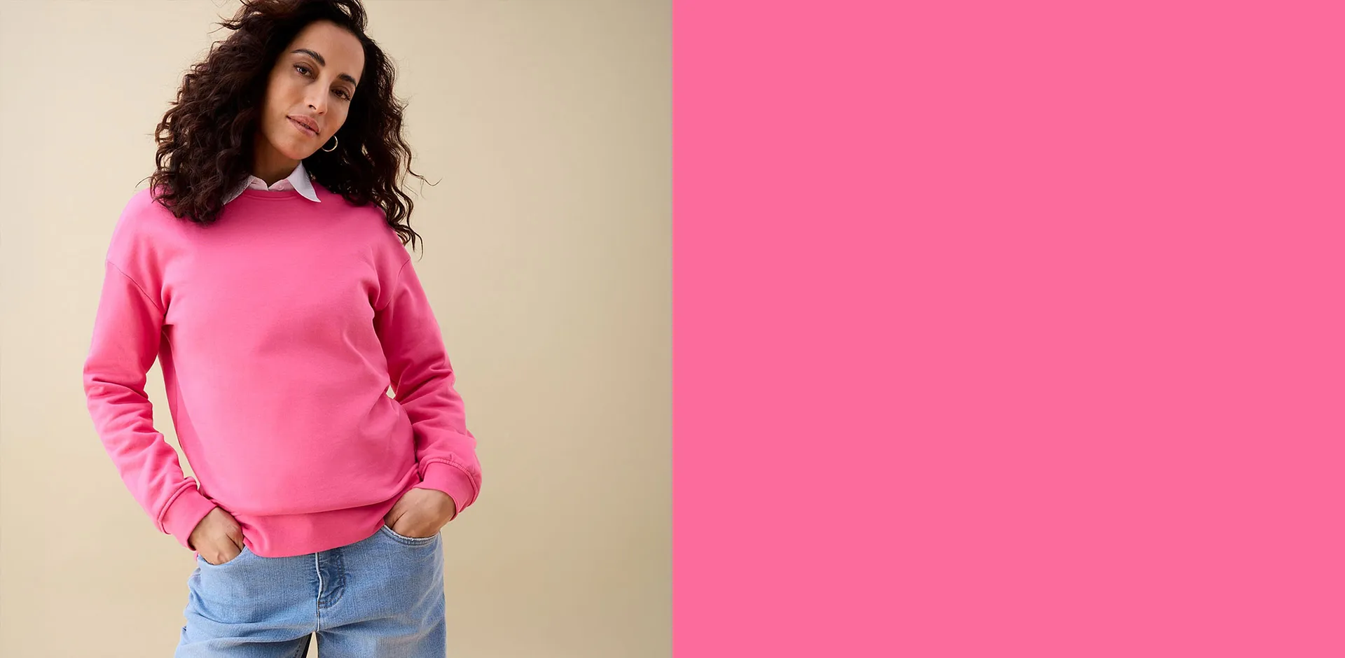 Una felpa rosa sopra una camicia bianca, abbinata a un paio di jeans blu casual.
