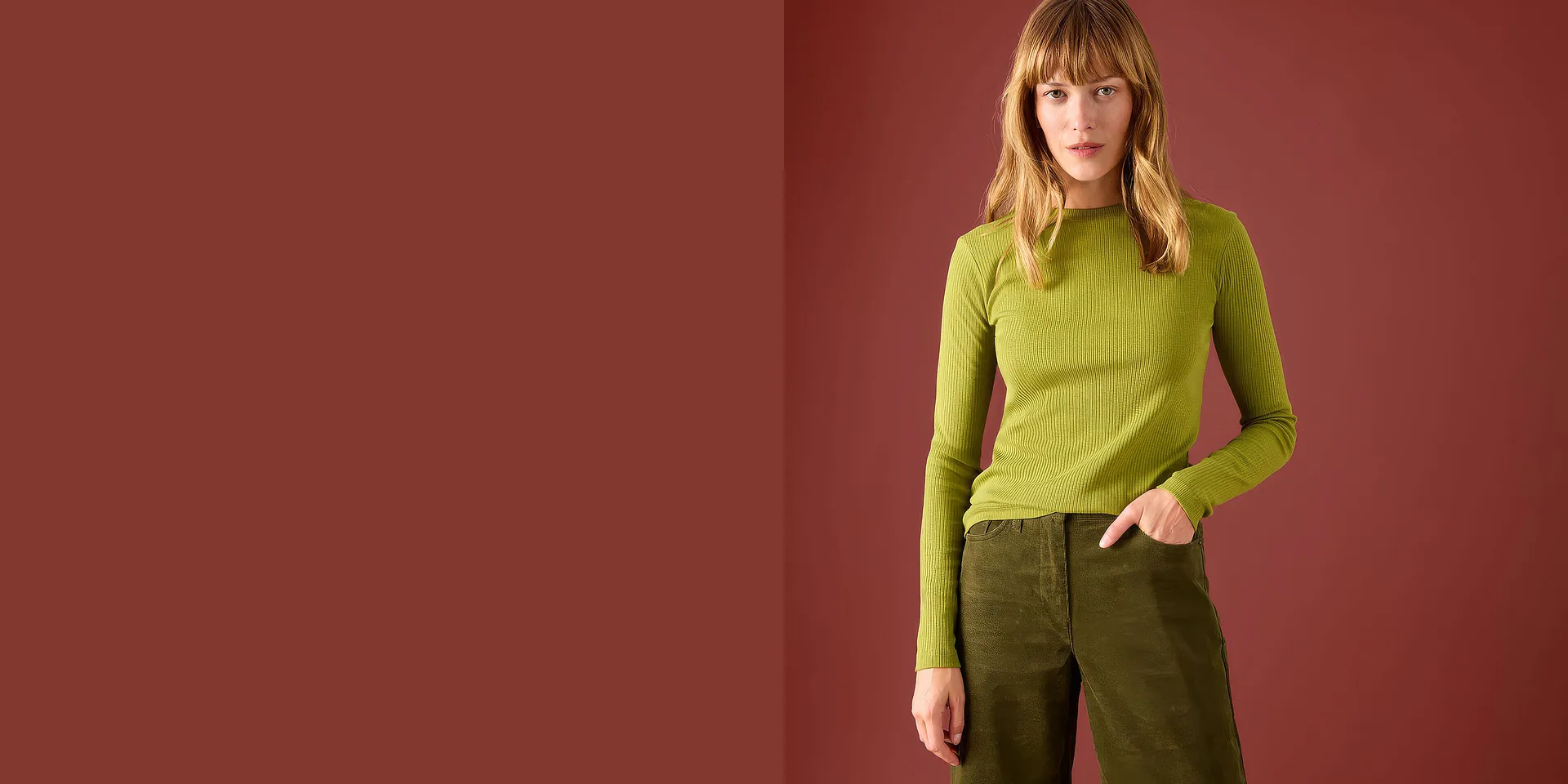 Una maglietta verde a maniche lunghe a costine si abbina a un paio di pantaloni di velluto a coste dal taglio ampio e casual.
