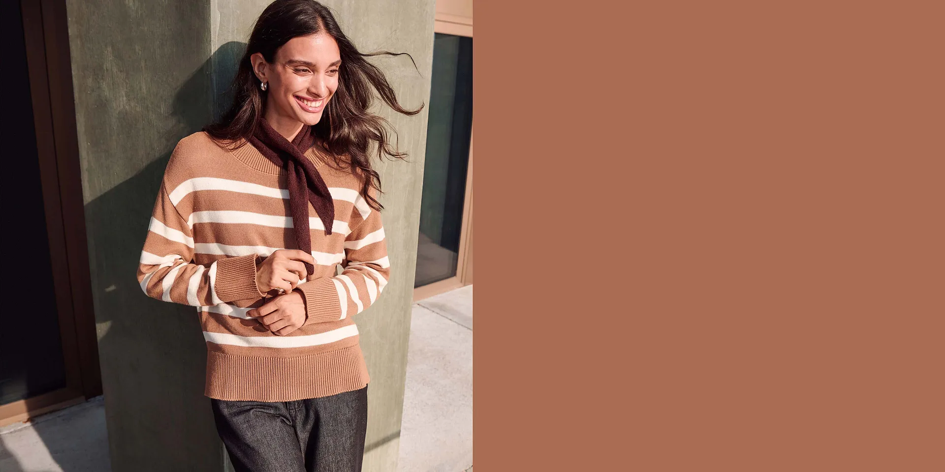 Maglione a righe marroni, sciarpa scura e pantaloni fantasia: un look elegante e comodo.
