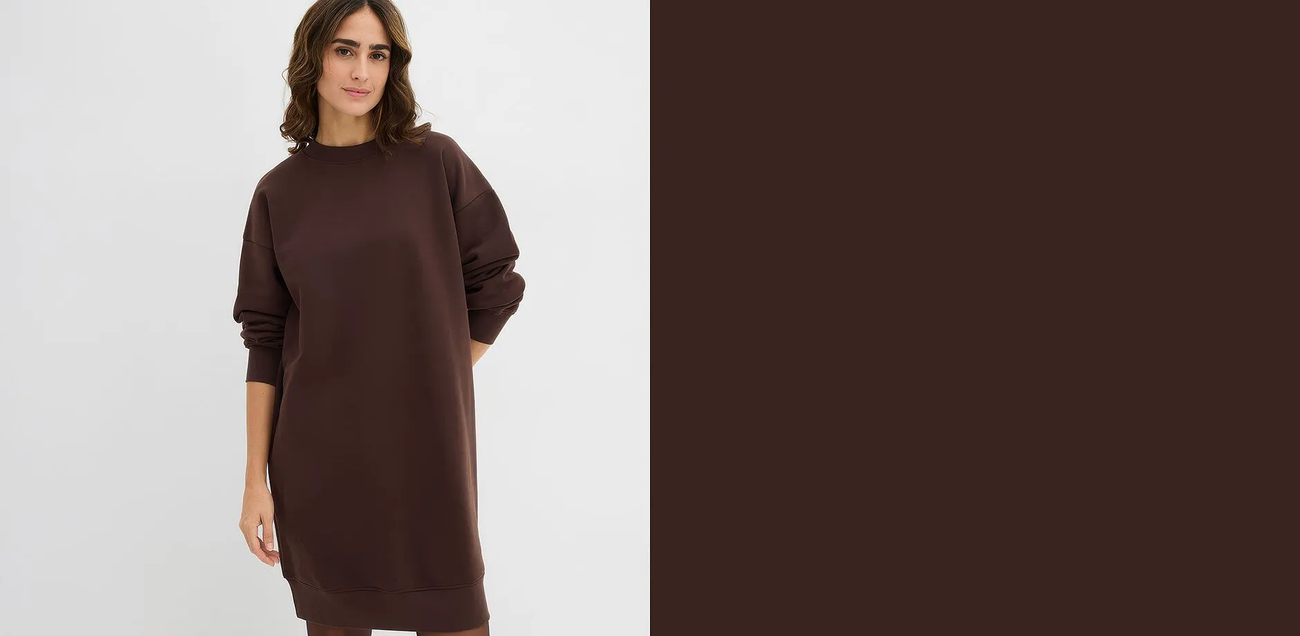 Una donna indossa un abito in felpa lungo, dalla vestibilit&agrave; ampia, di colore marrone scuro.
