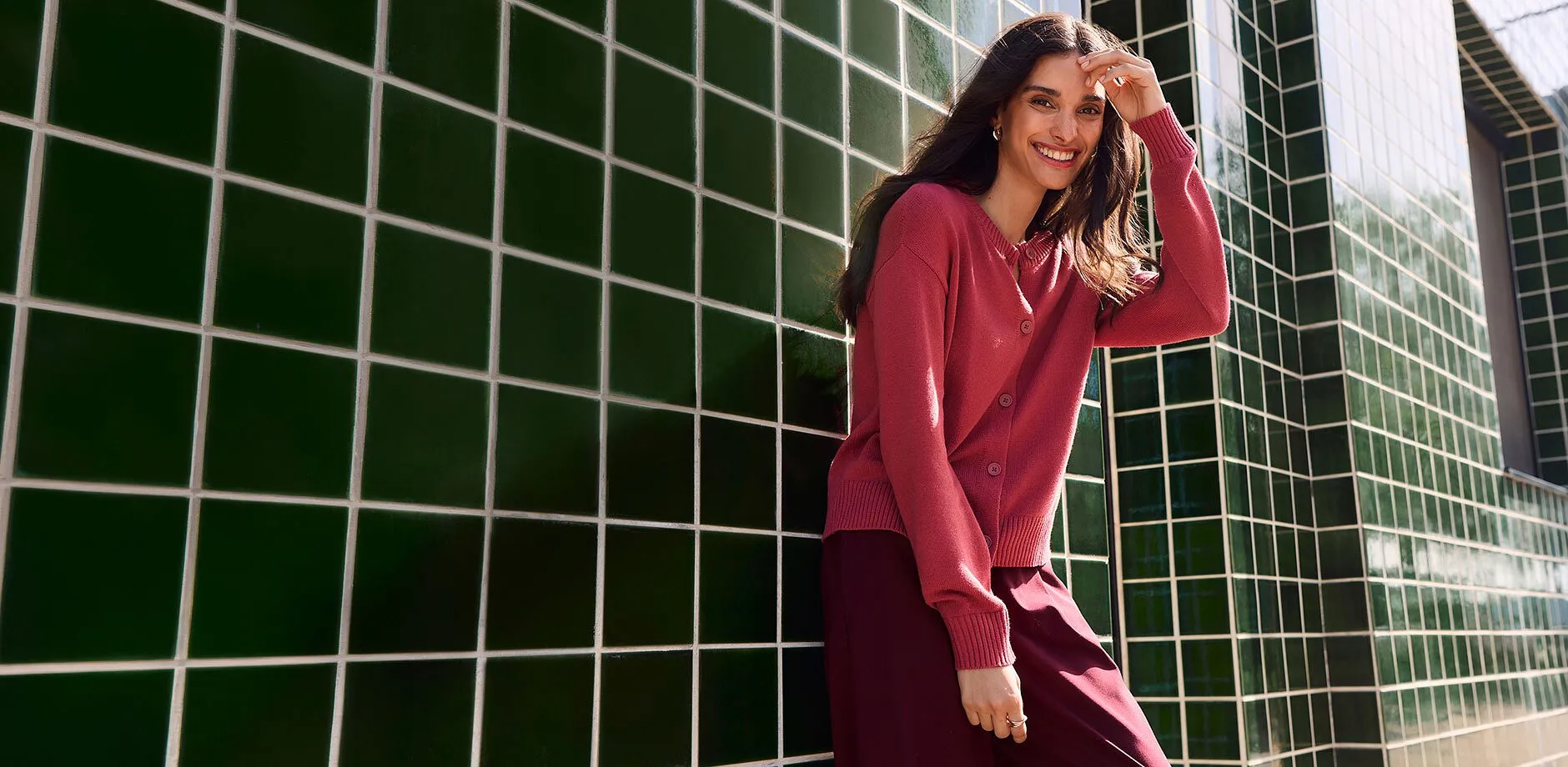 Un cardigan rosa lavorato a maglia con bottoni e una gonna scura e fluida.