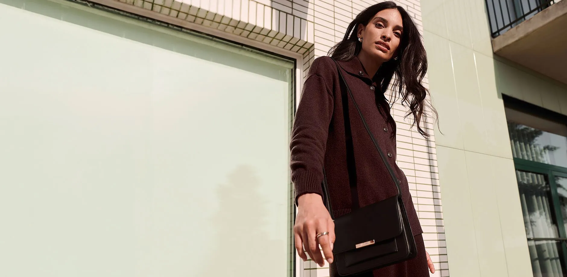 Un cardigan scuro, un'elegante borsa nera e gioielli discreti per un look raffinato.