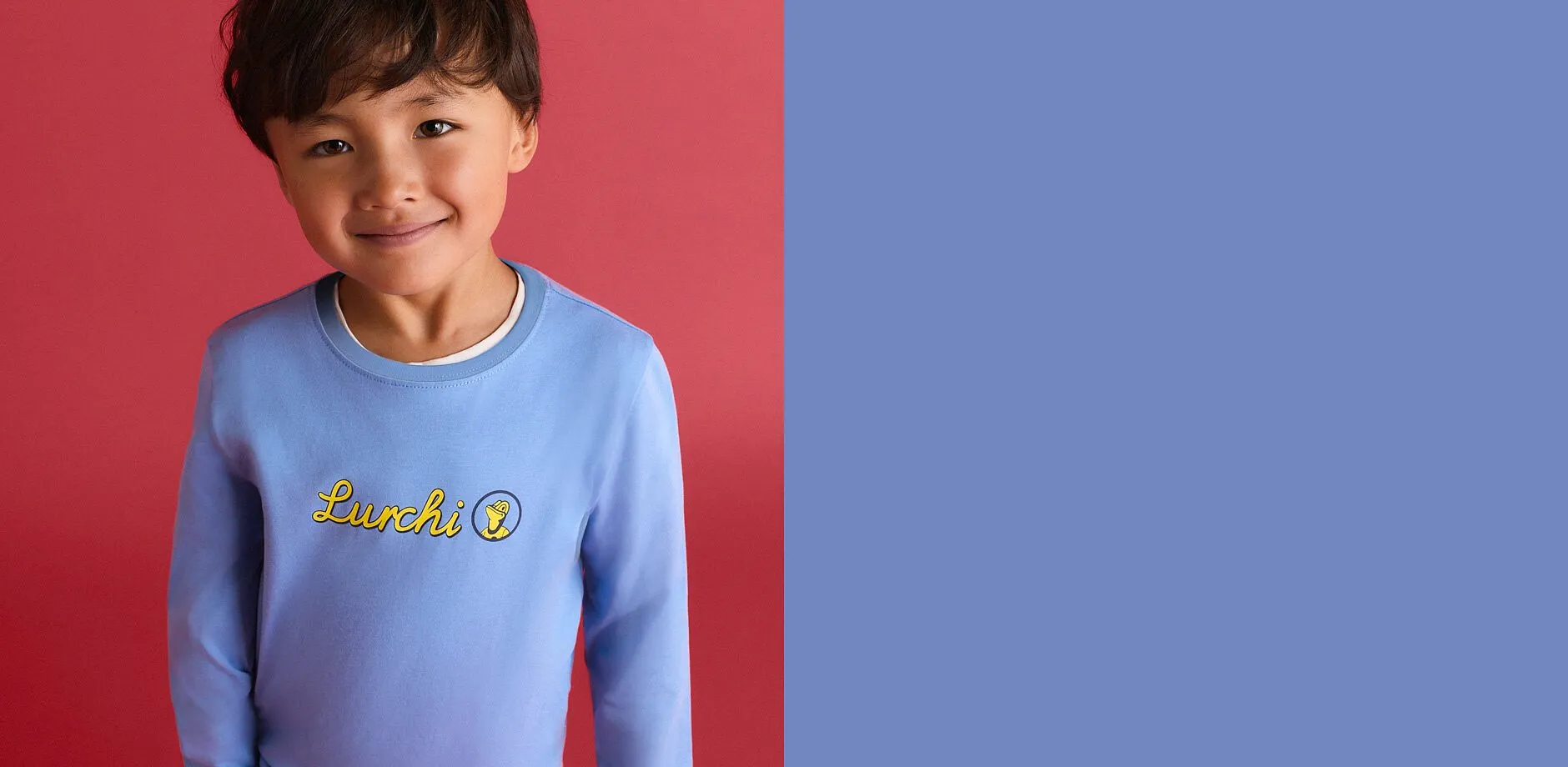 Il bambino indossa una maglietta a maniche lunghe azzurra con la scritta &ldquo;Lurchi&rdquo; in giallo.