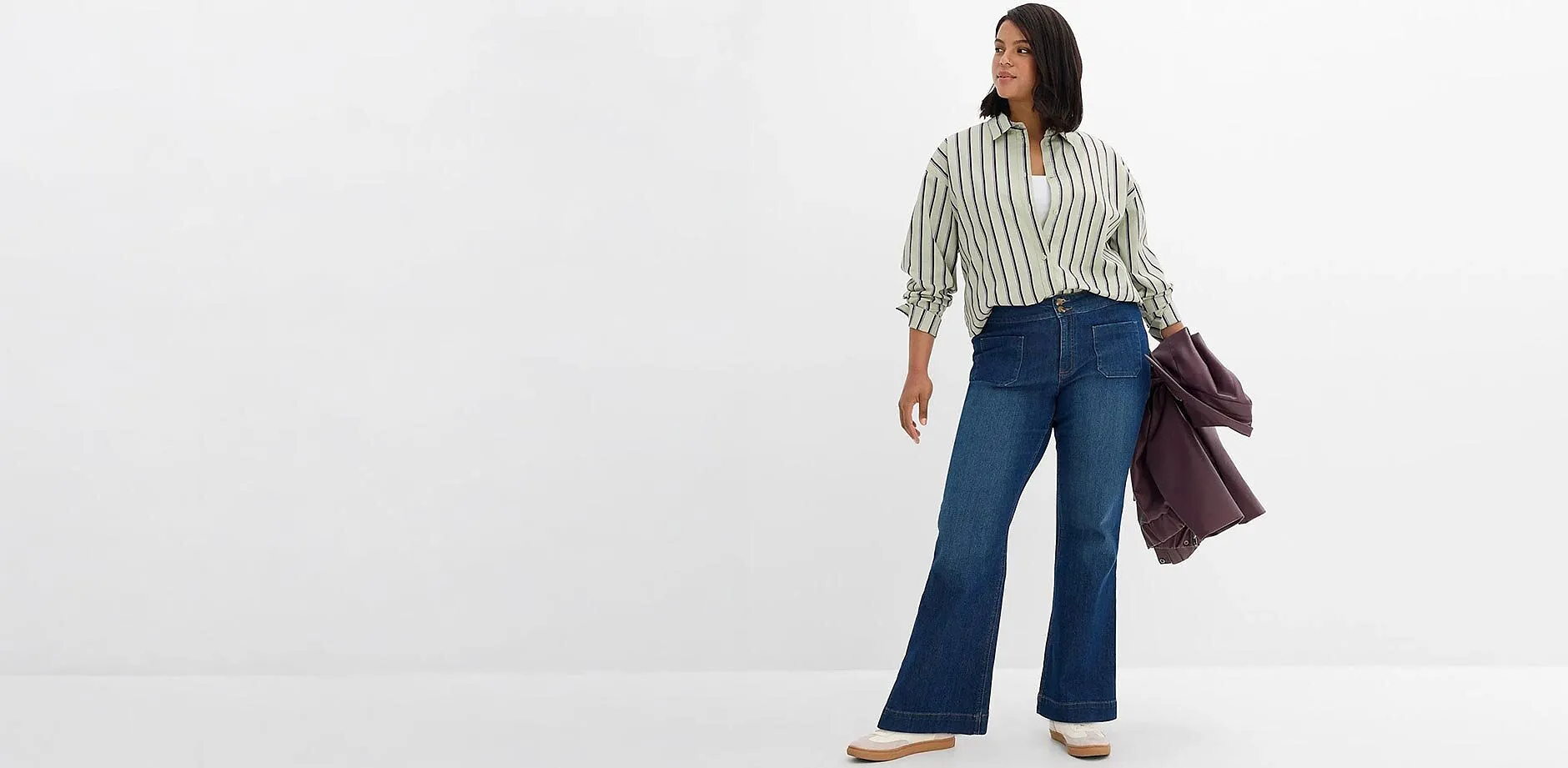 Outfit casual: camicia a righe, jeans a zampa blu e una giacca alla moda.