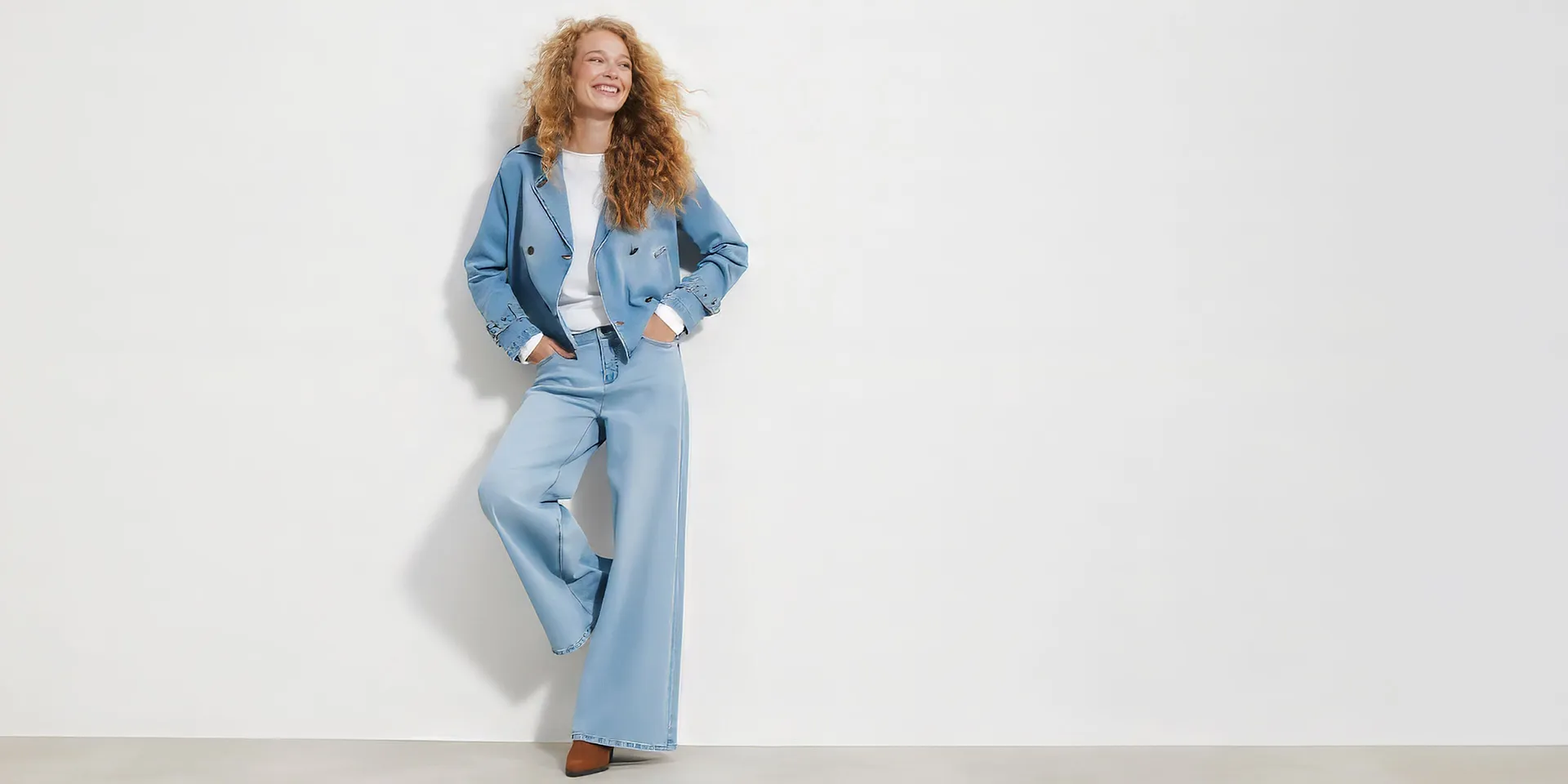 Giacca di jeans corta, pantaloni larghi, maglietta bianca e scarpe marroni.