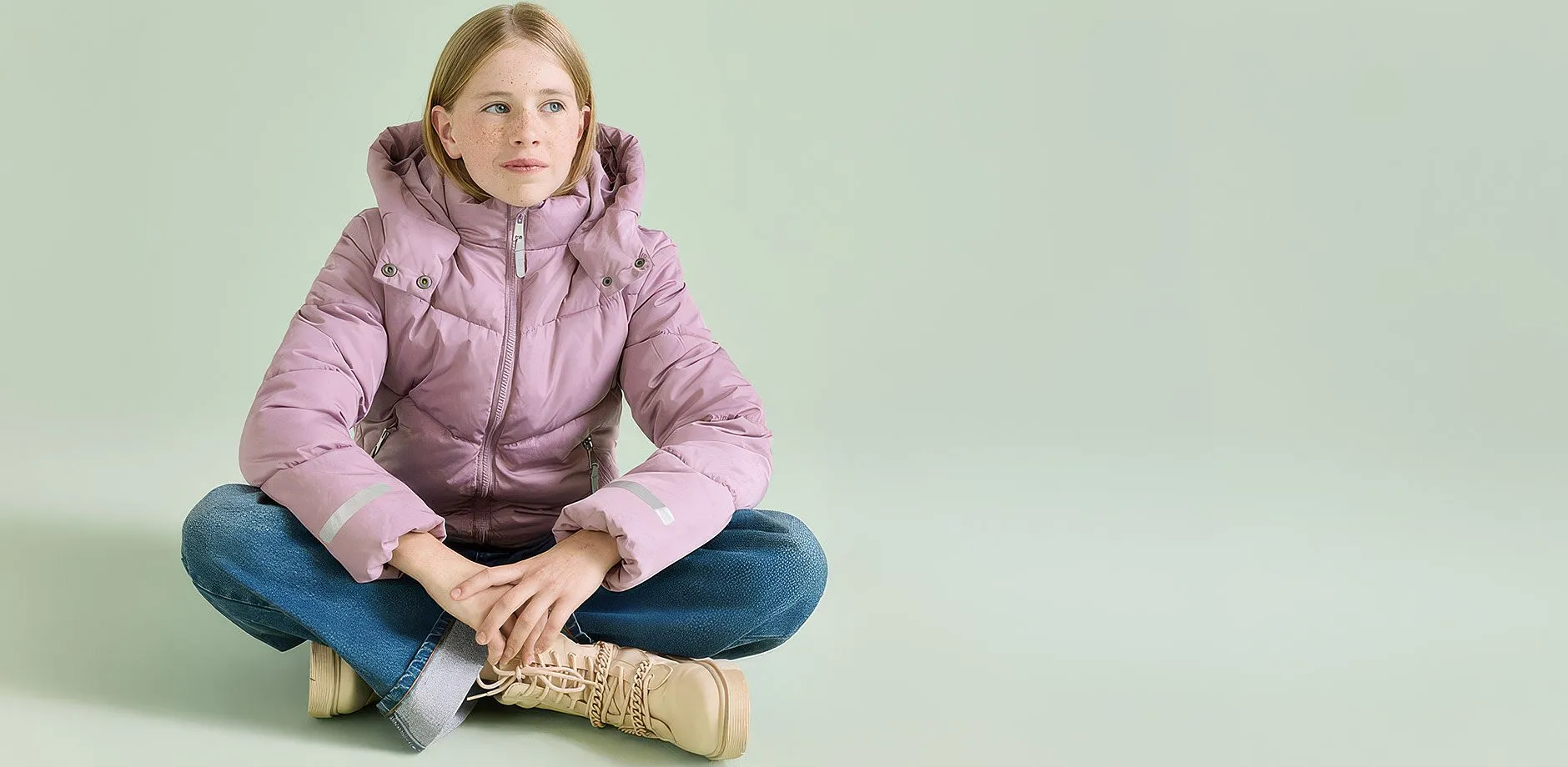 Una giacca trapuntata rosa, dei jeans blu e degli stivali beige creano un outfit che tiene caldo.
