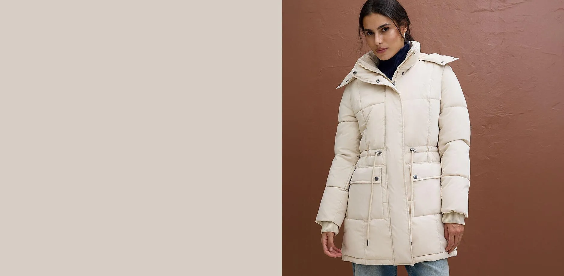 Giacca trapuntata alla moda color crema indossata sopra un maglione a collo alto scuro e jeans chiari.