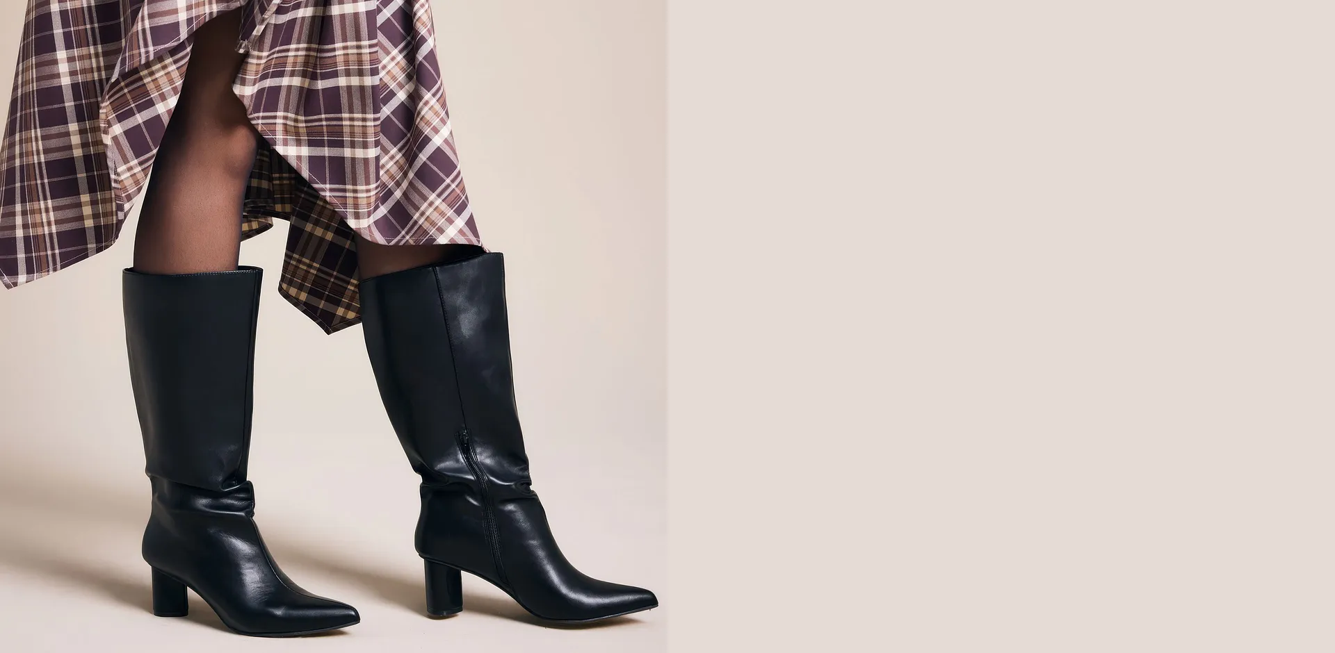 Un look alla moda: gonna a quadri, collant neri ed eleganti stivali neri.