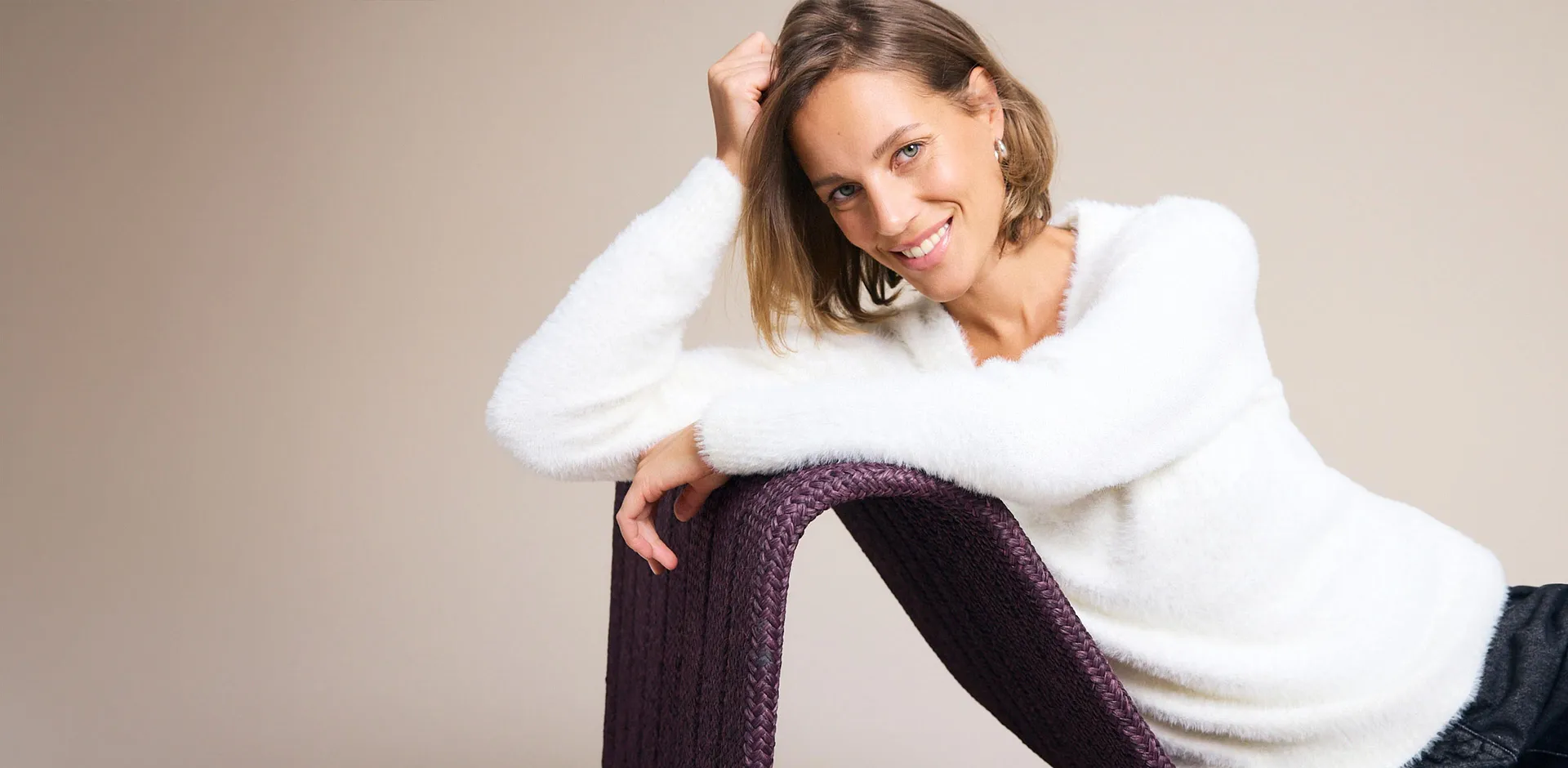 Un maglione bianco e soffice e dei pantaloni scuri sottolineano lo stile disinvolto.